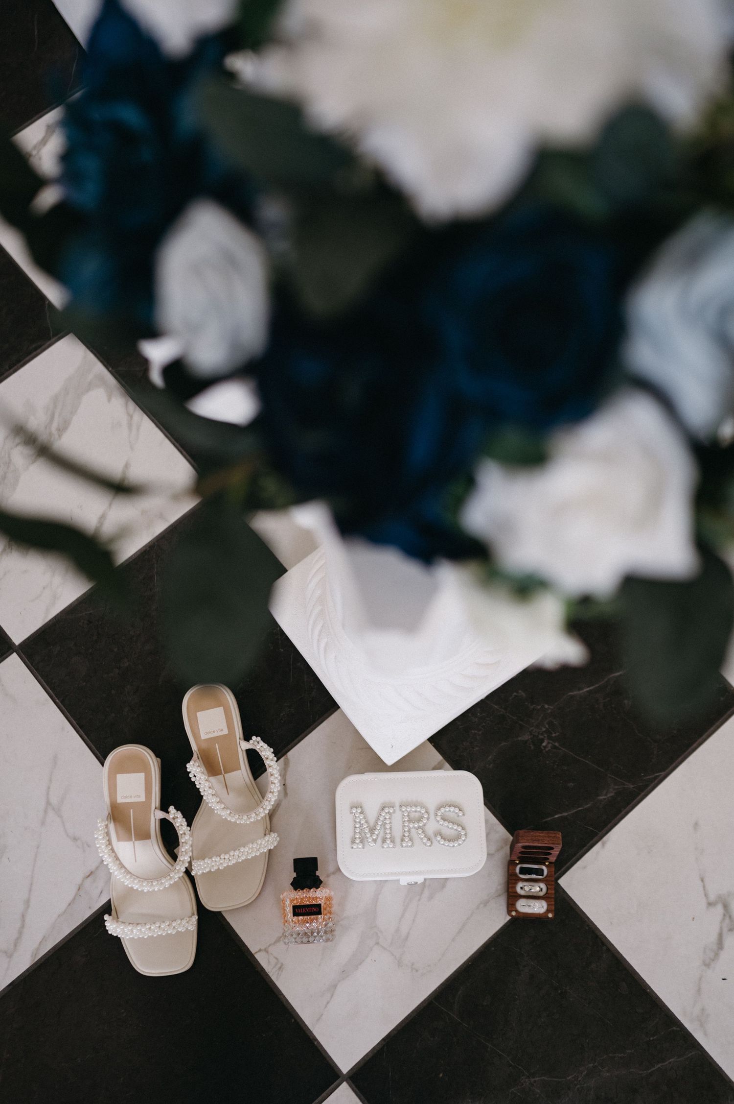Wedding shoes and accessories artistically arranged on a black and white checkered surface.