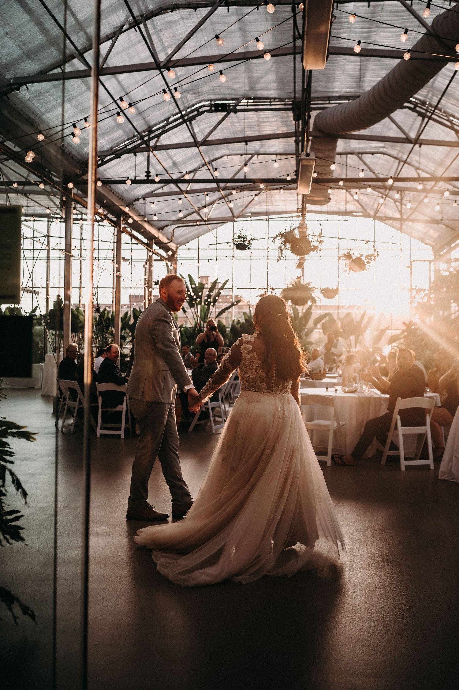 Couple sharing their first dance in a sunlit greenhouse reception venue.