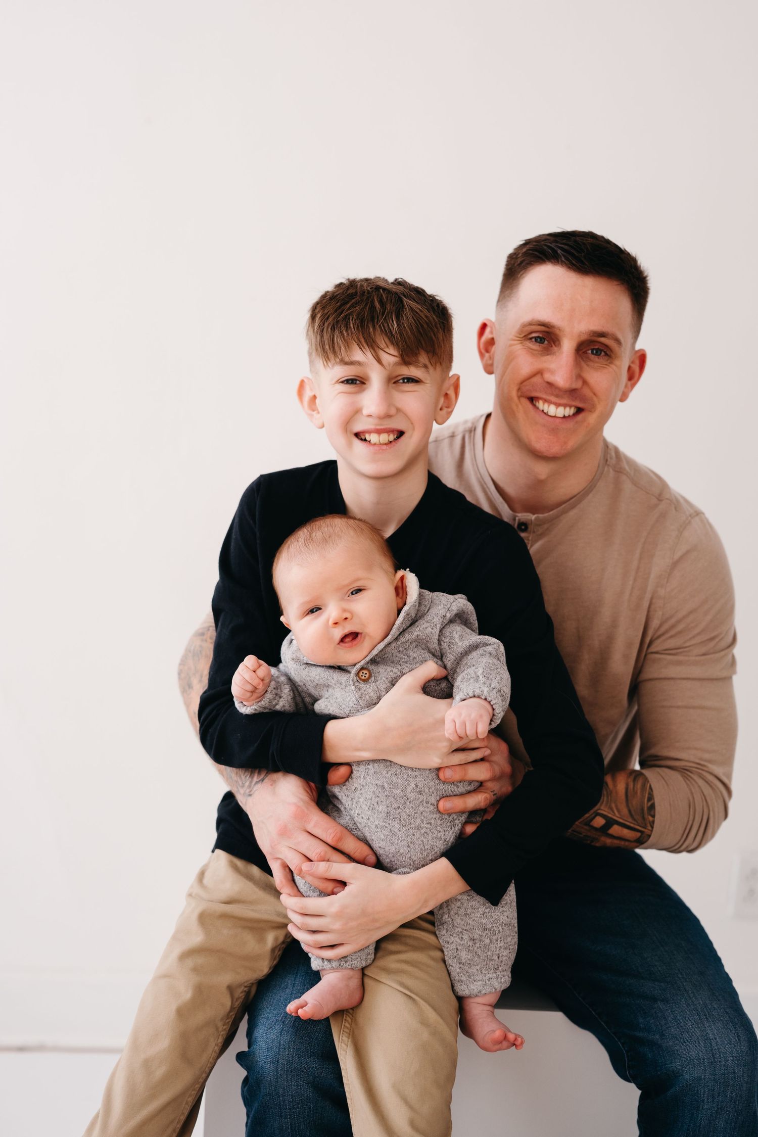 Three family members share a joyful moment together against a simple white background.
