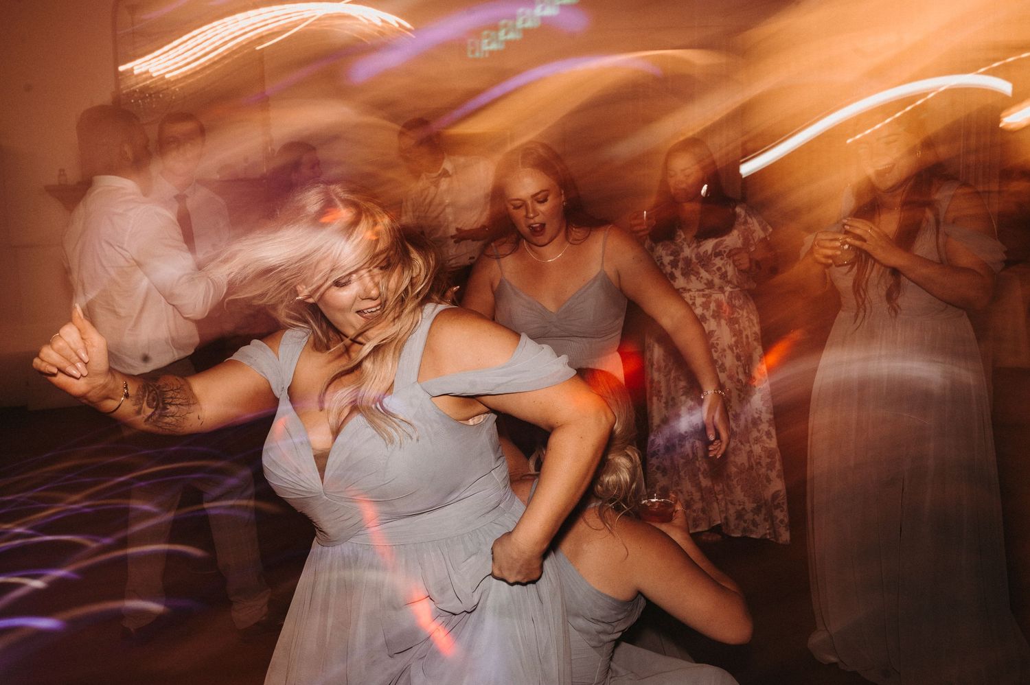 Motion-blurred photograph of wedding guests dancing energetically at reception.
