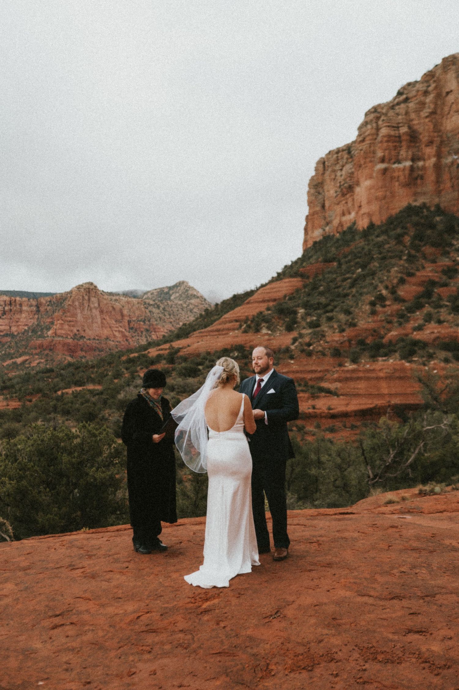 Wedding ceremony taking place on red rocks with dramatic Sedona cliffs in the background.