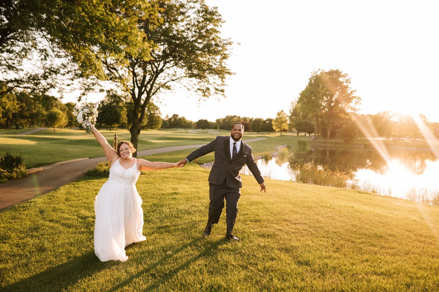 A couple dances and twirls in a golden field at sunset creating a romantic silhouette against the warm light.