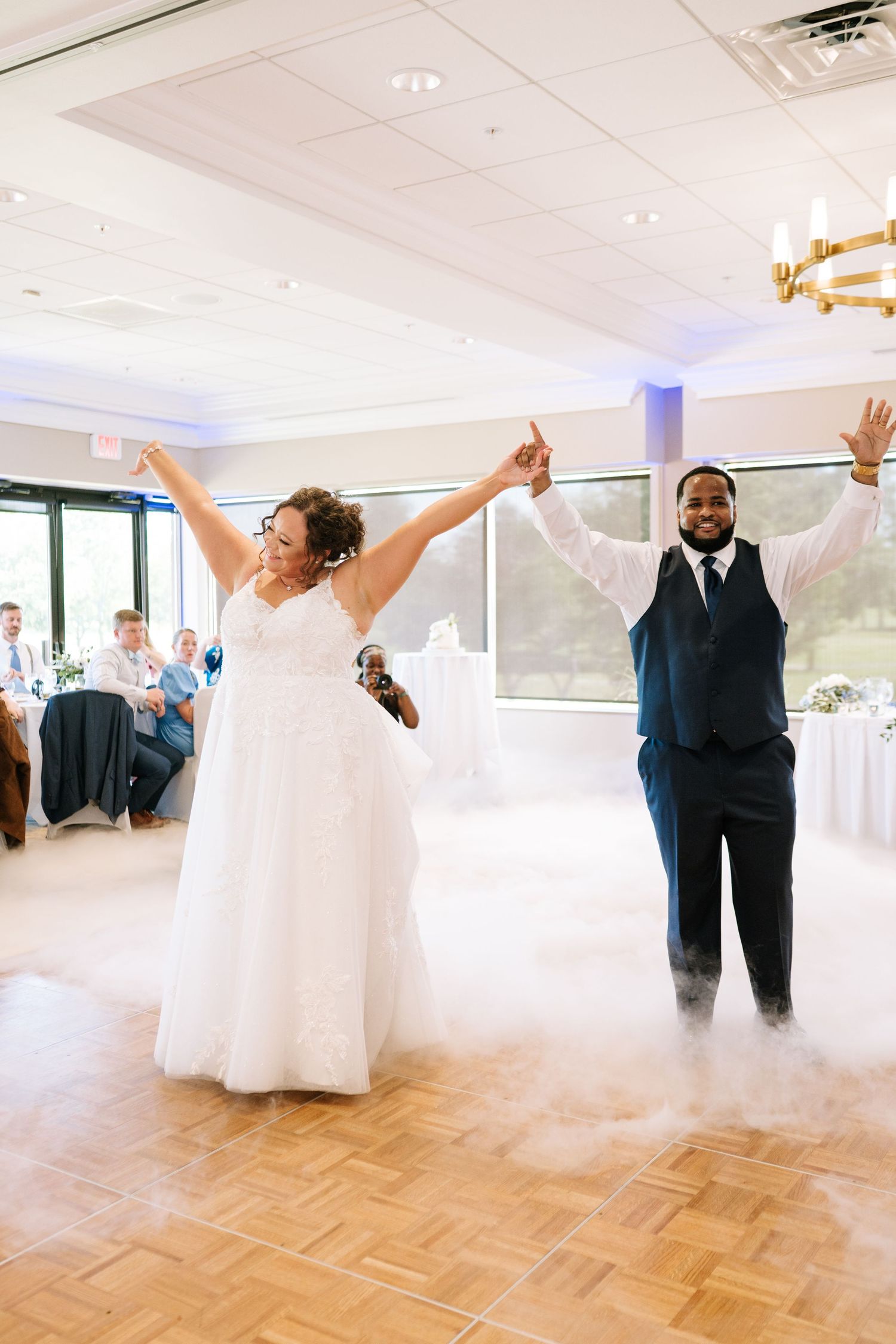 Wedding celebration in bright ballroom with couple dancing on parquet floor.
