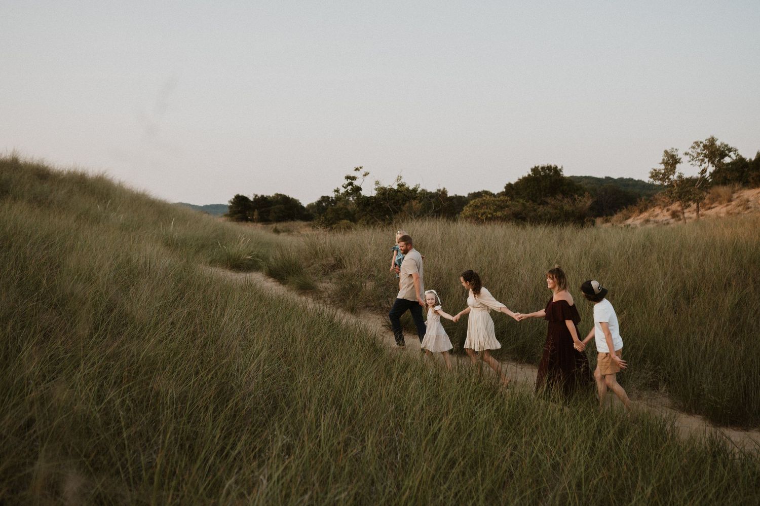Silhouettes of people walking together through a golden grass field at sunset.