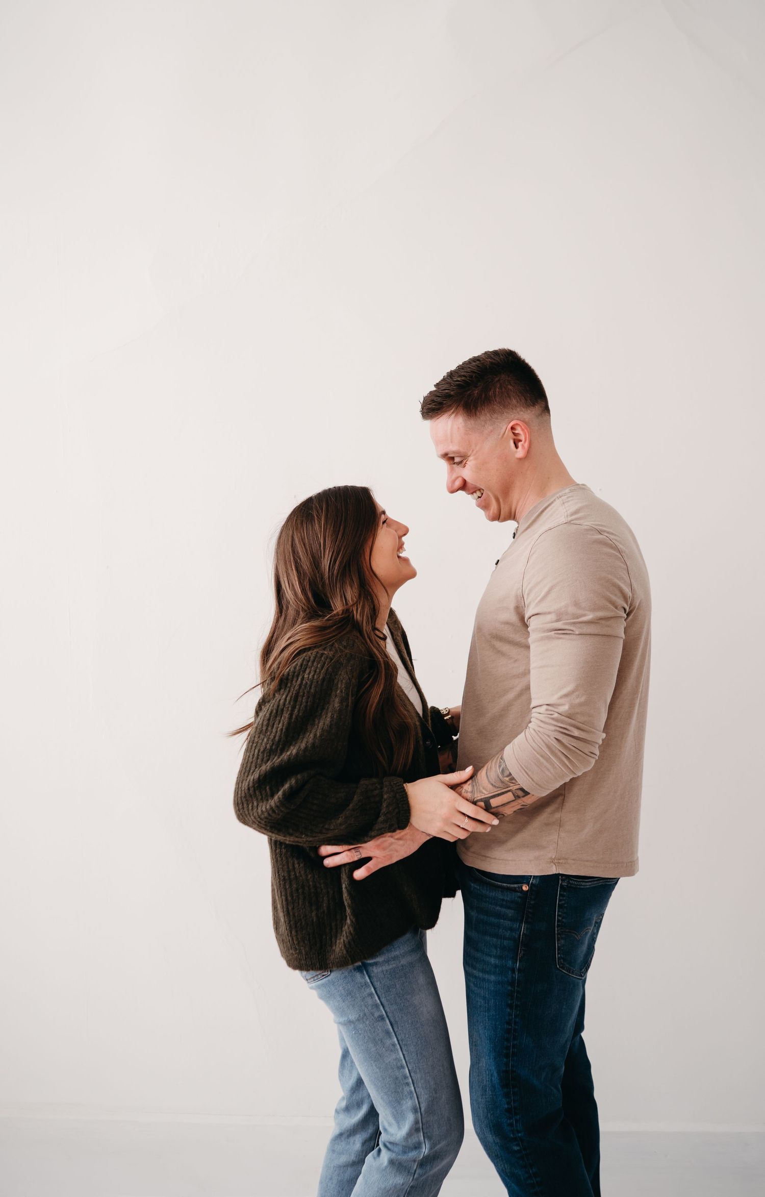 Couple sharing intimate moment while standing against white background.