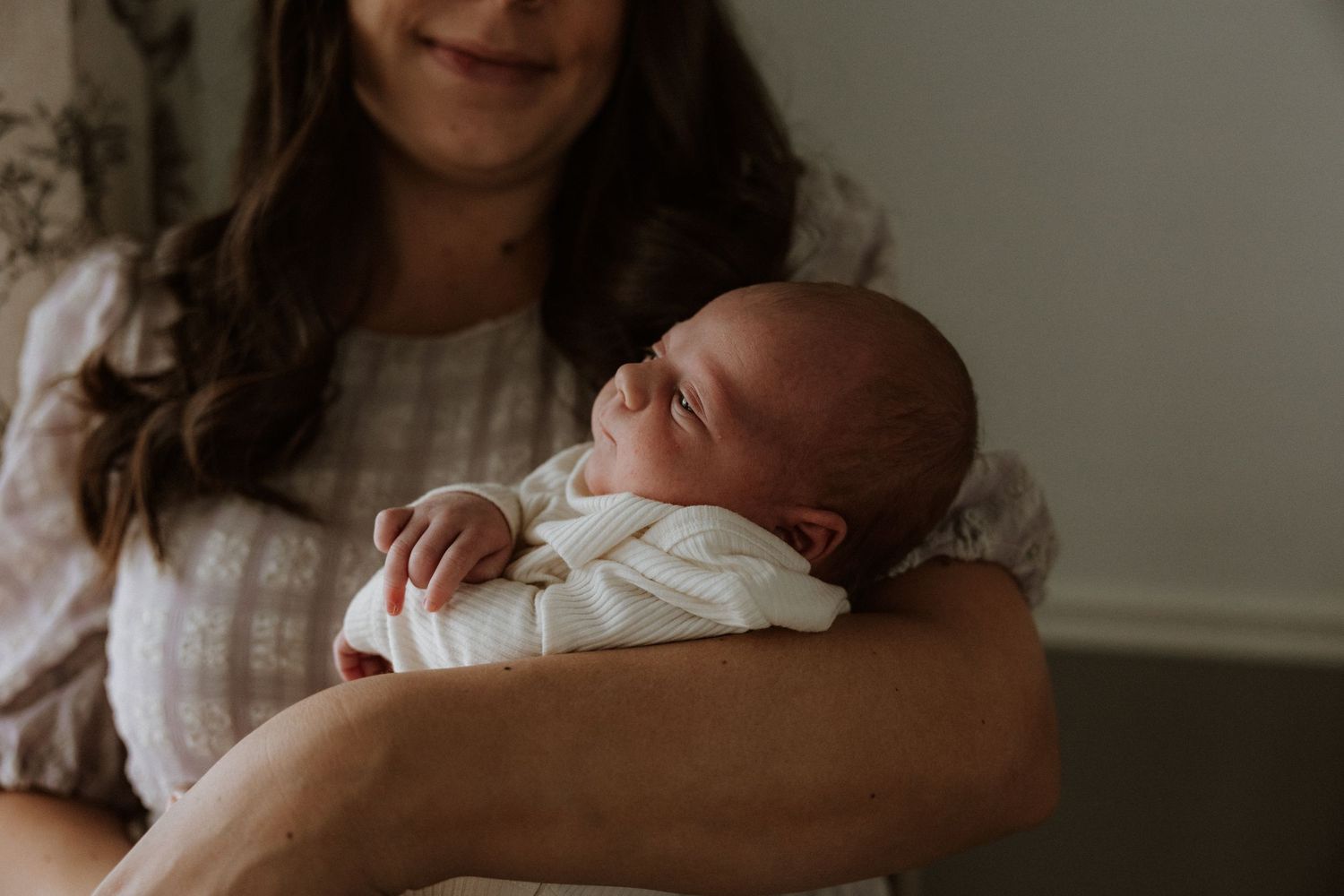A peaceful scene of a newborn baby sleeping while being cradled in white clothing.