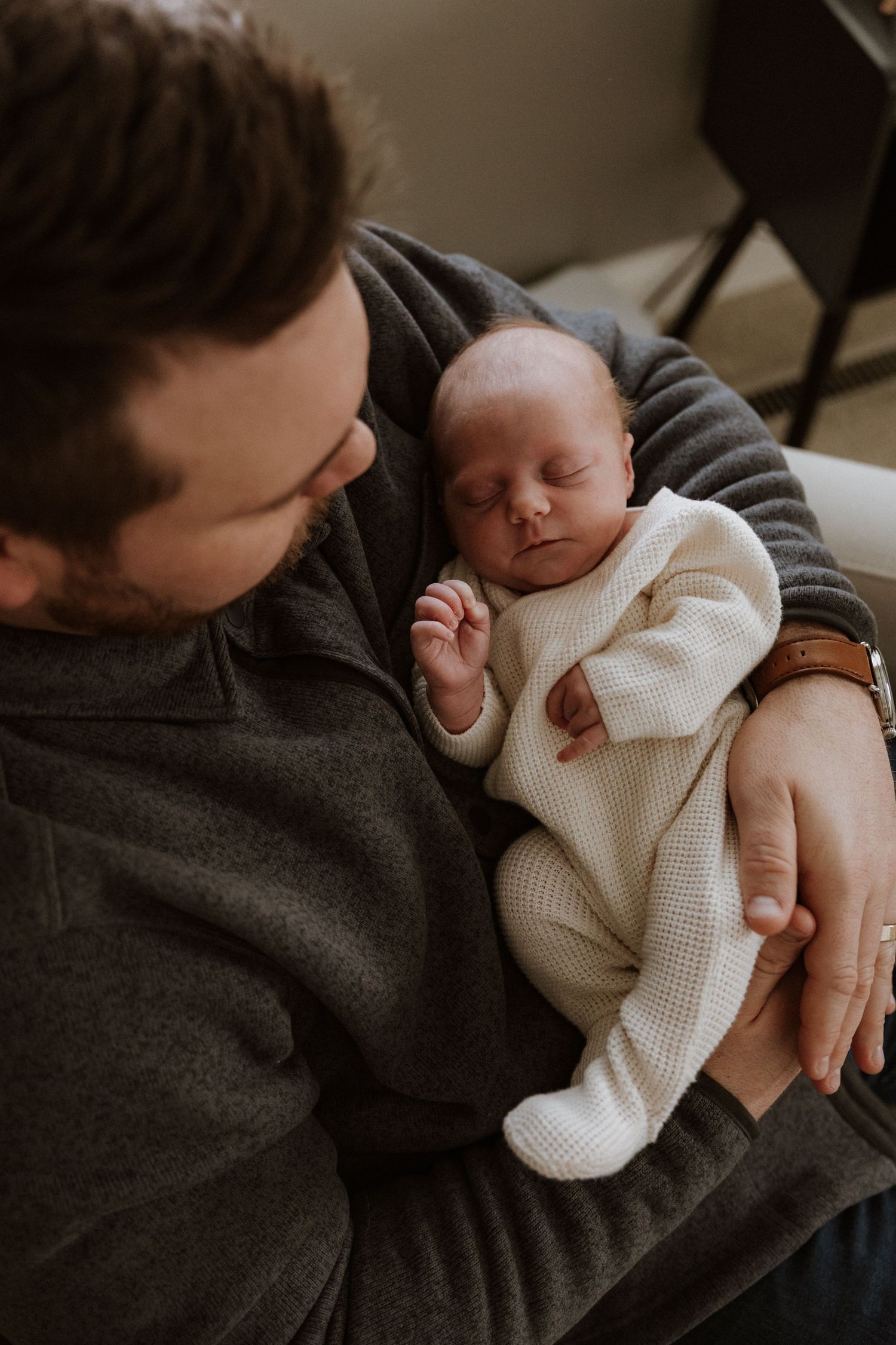 A series of intimate portraits showing tender moments between parent and newborn wearing a white sweater.