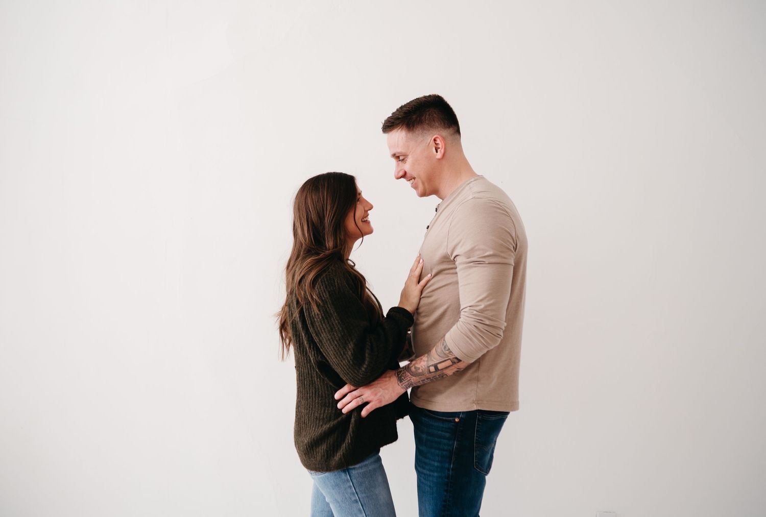 Couple in casual clothing sharing an intimate moment against a white backdrop.