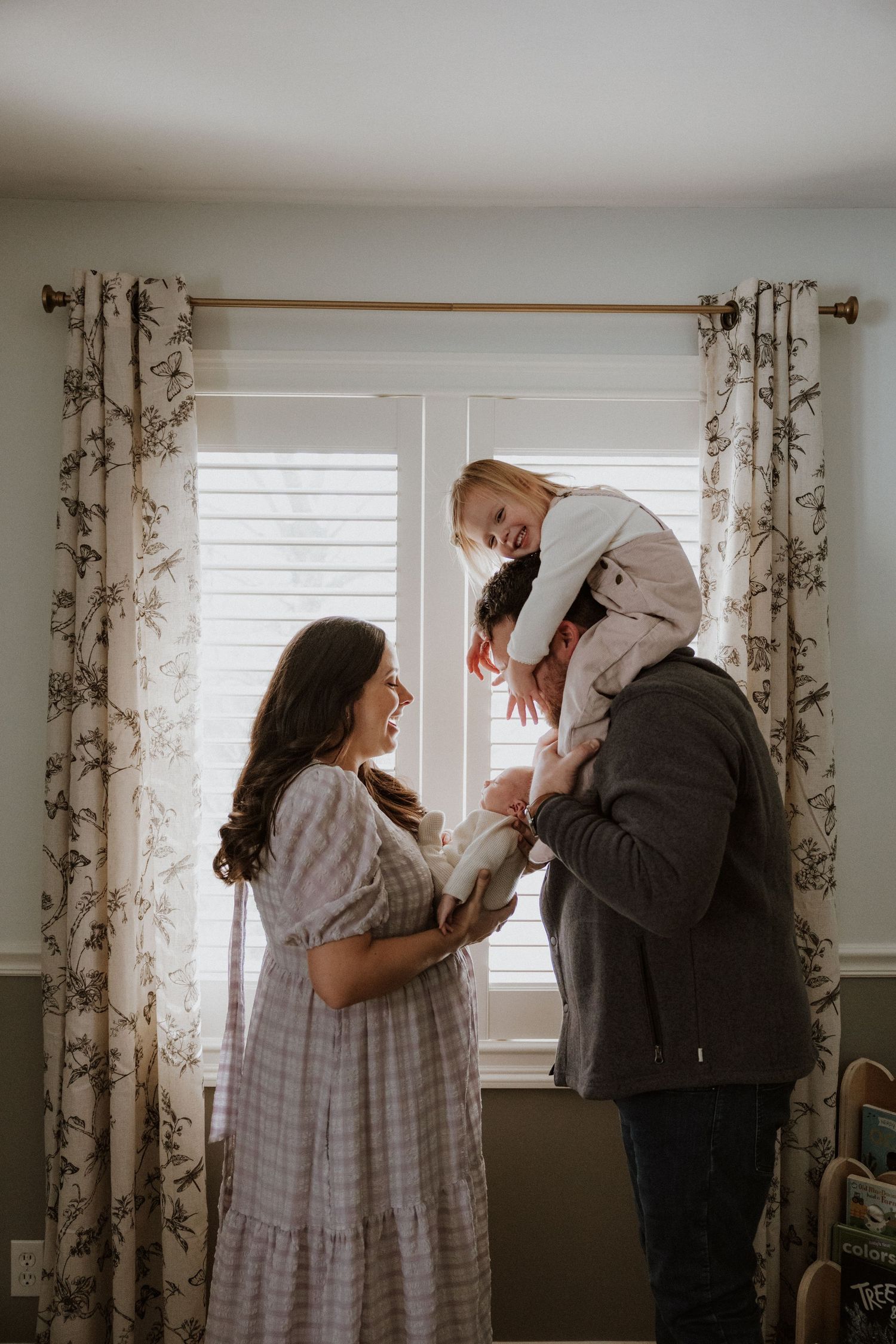 A tender moment captured in a series of intimate family photos with floral curtains and natural window light.