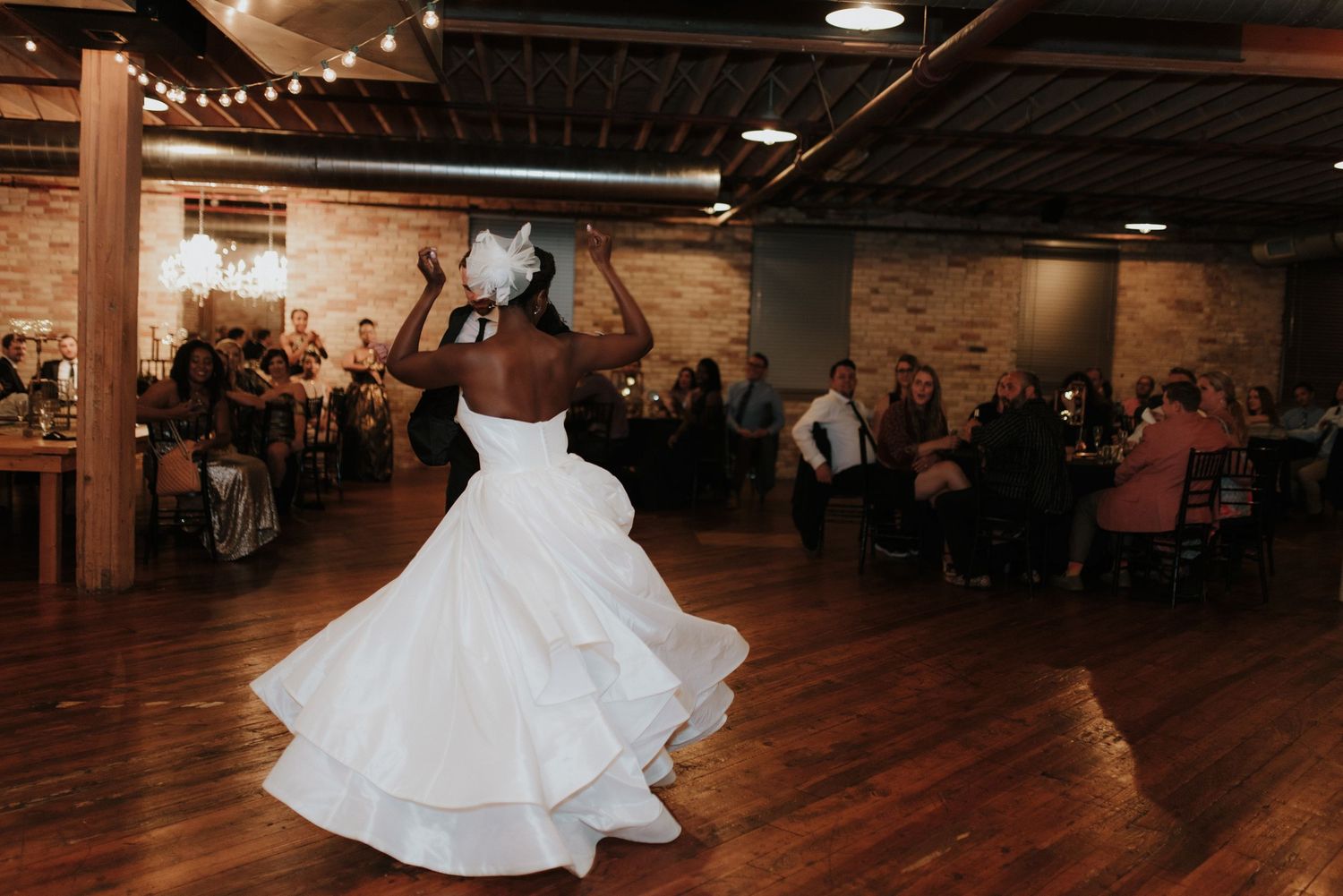 Wedding celebration on a rustic wooden dance floor with string lights overhead.