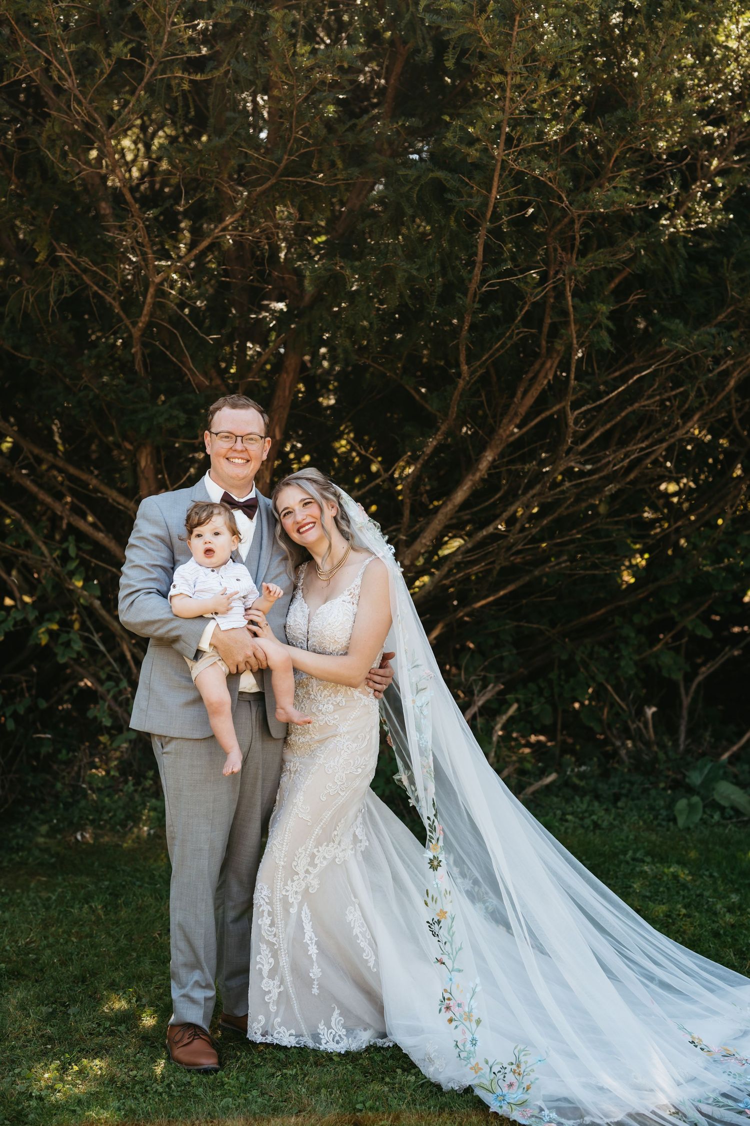 Family in formal attire poses together in garden setting.
