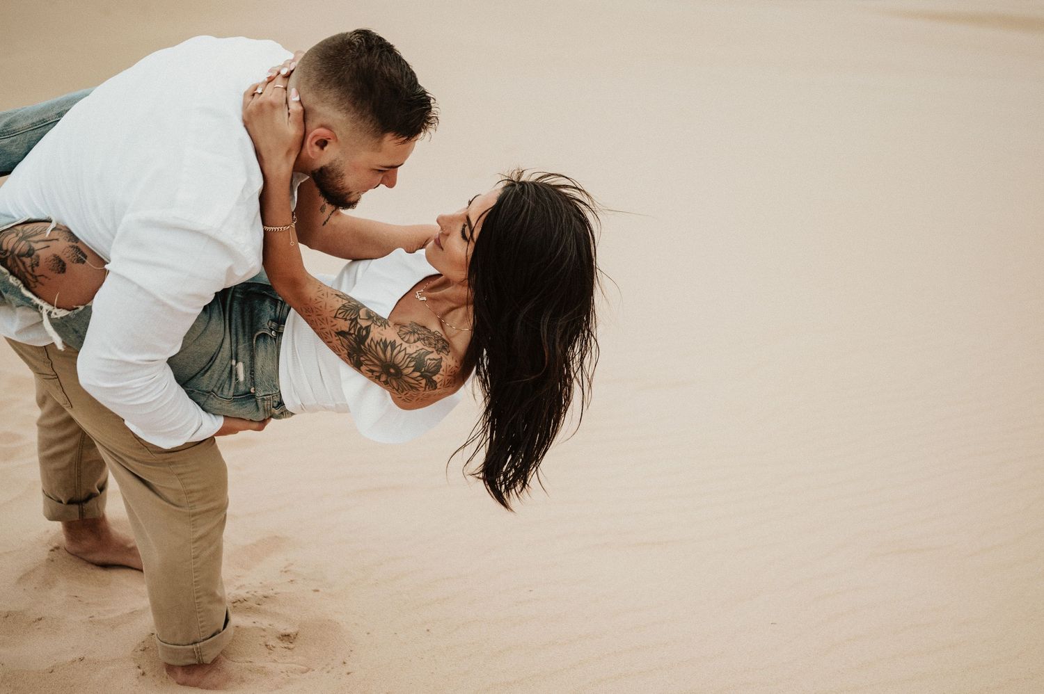 A romantic dip pose on desert sand dunes with dramatic overcast sky.