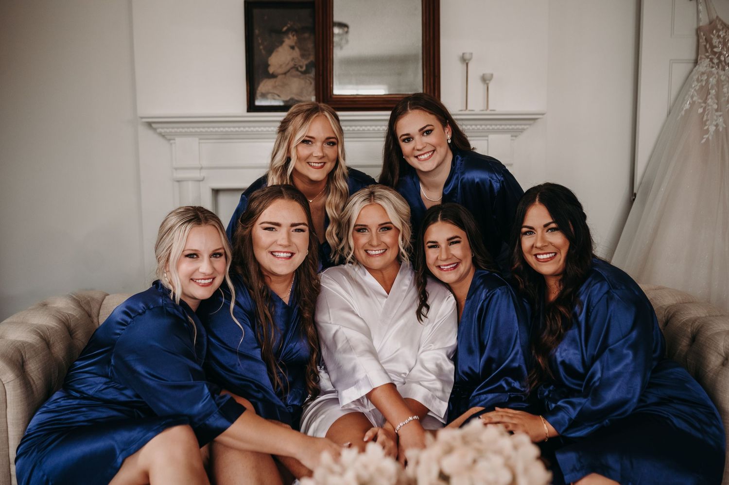 Wedding party wearing matching navy robes pose together on a couch.