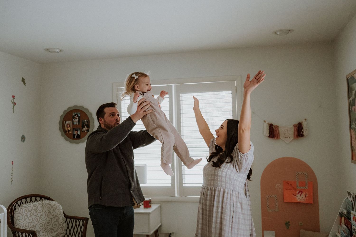Family celebrating and dancing together in a bright white living room with joyful energy.