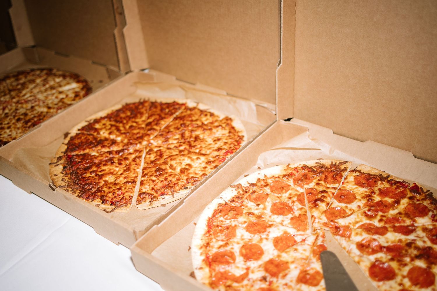 Open pizza boxes showing fresh pepperoni pizzas at wedding reception.