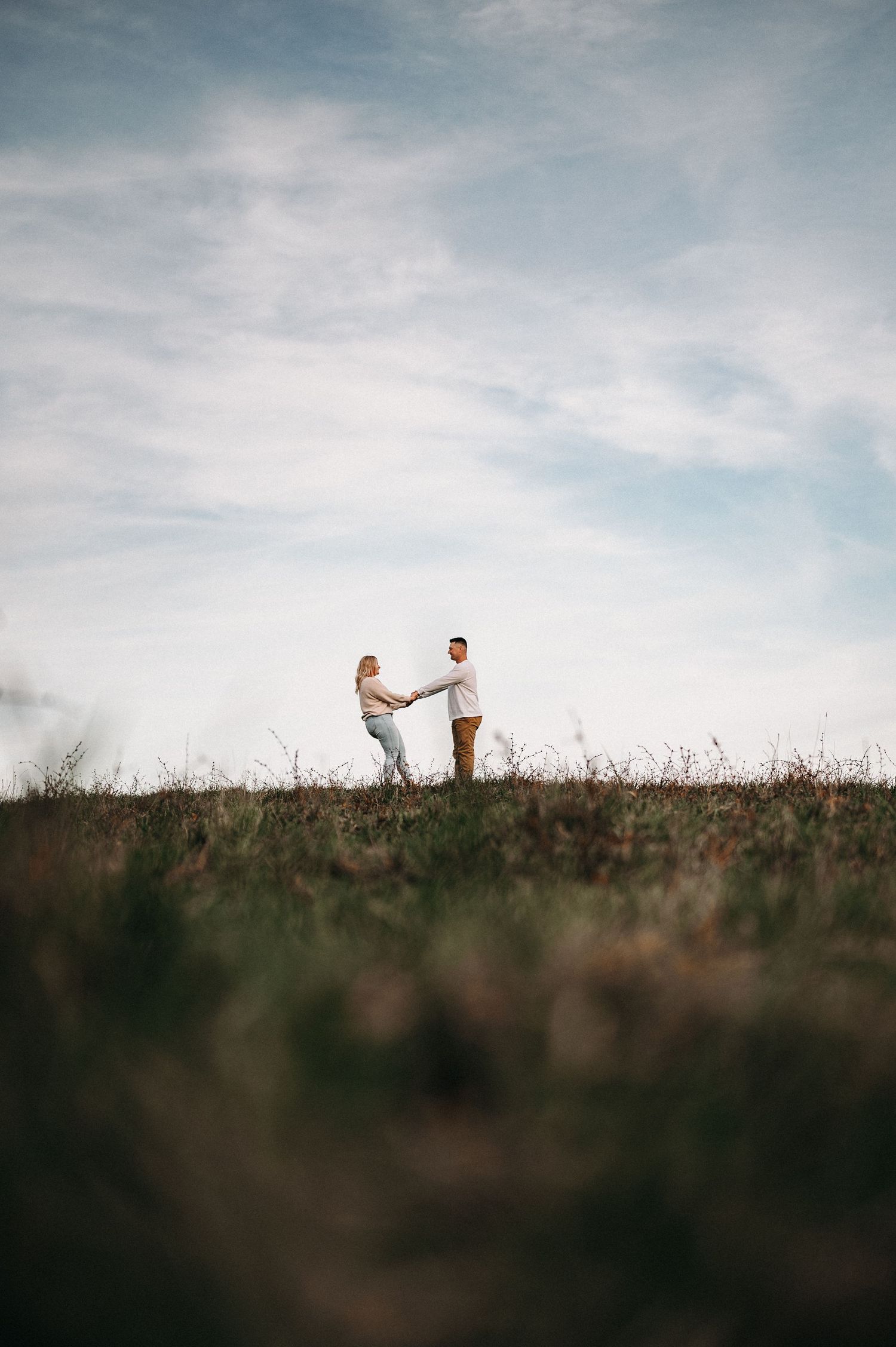 Distant view of two people standing together on a hilltop during golden hour.