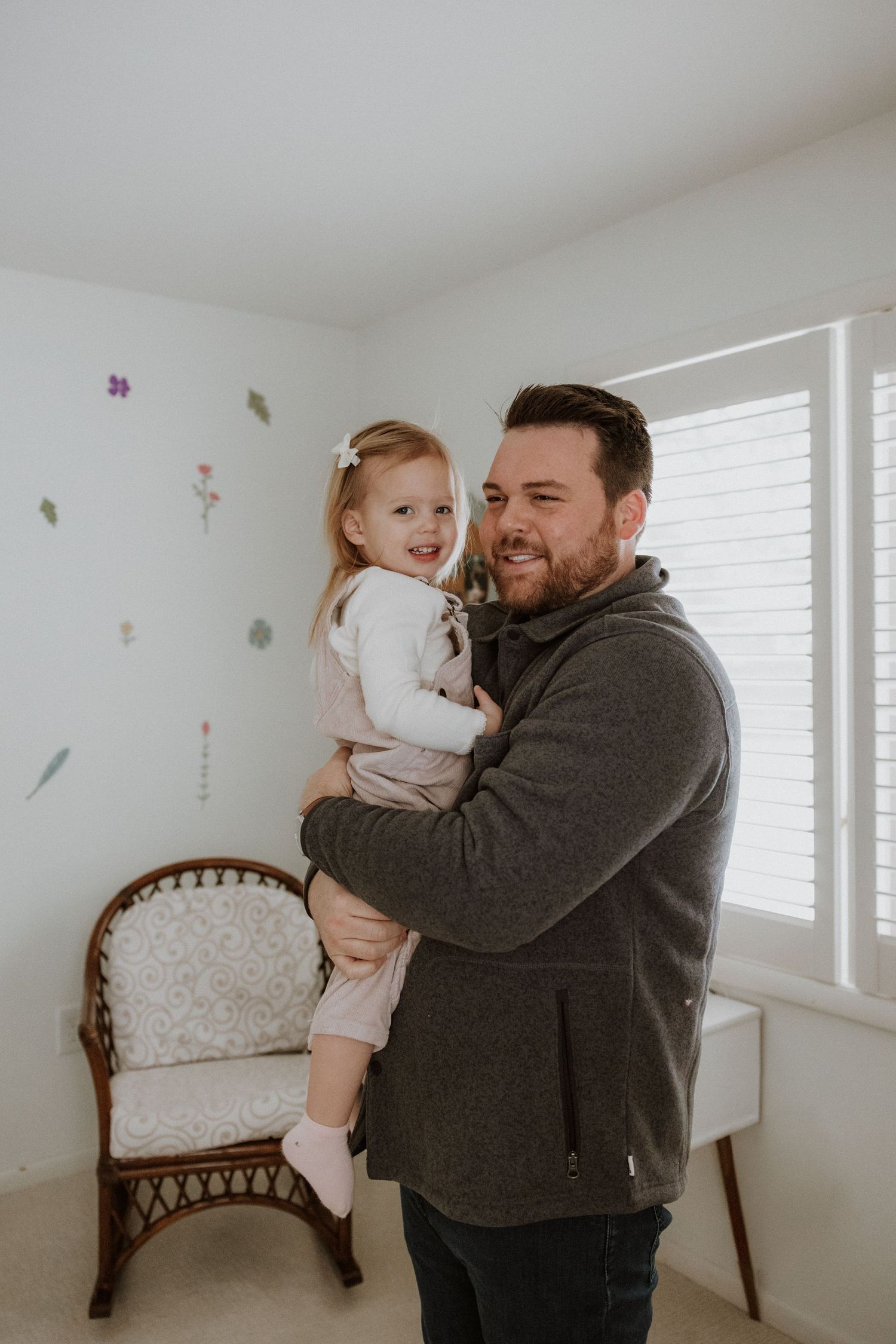 A bright, airy room with white walls and windows showing joyful family interactions.