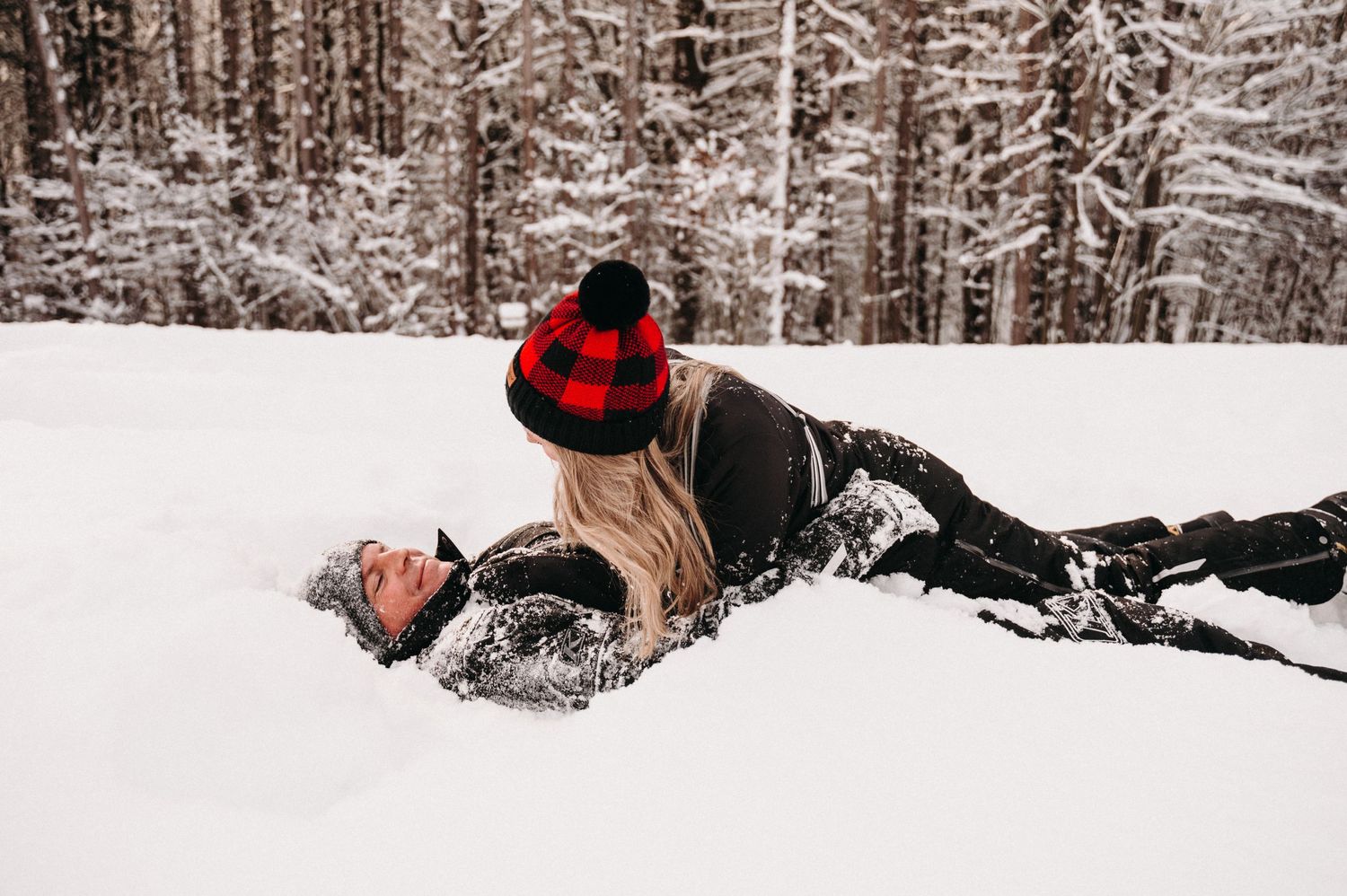 Playful winter scene with couple in black coats enjoying snow.