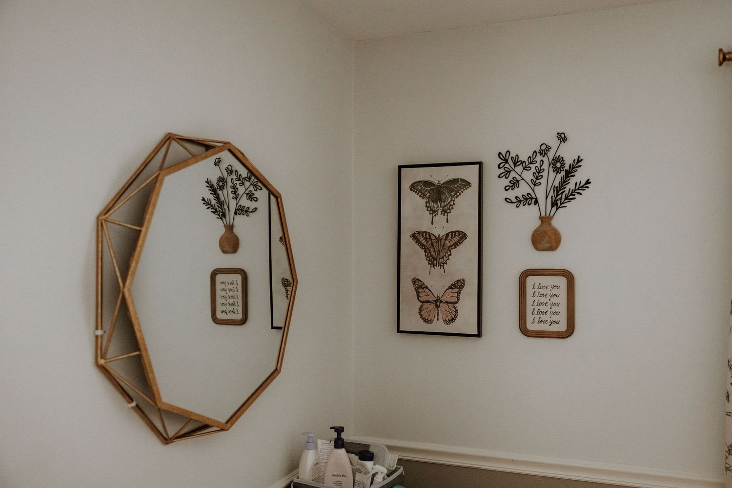 Minimalist wall decor featuring botanical prints and a geometric mirror in a neutral-toned room.