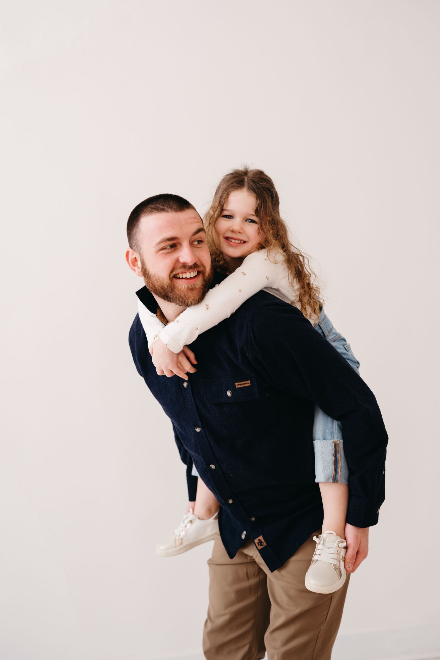A piggyback ride moment between parent and child against a light pink background.