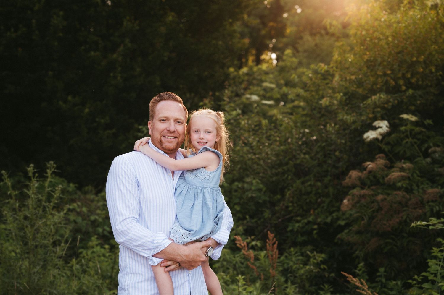 A tender moment captured at sunset with golden light filtering through trees in the background.