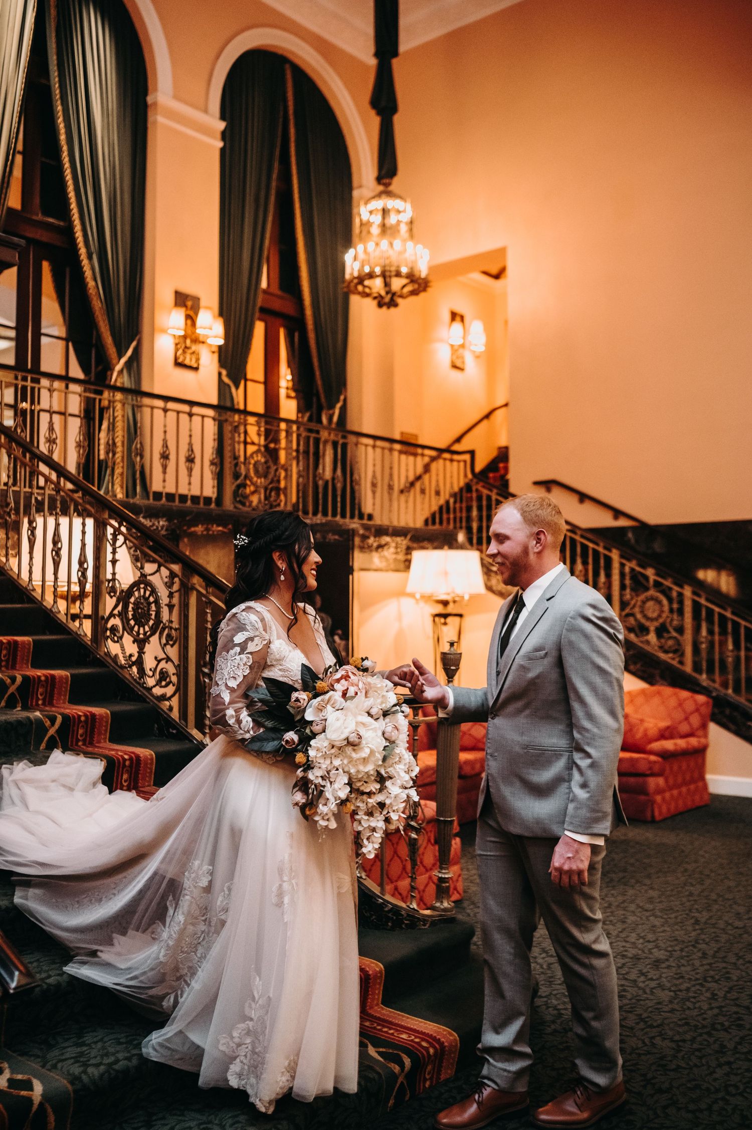 A romantic wedding scene on a grand staircase with crystal chandeliers and elegant decor.