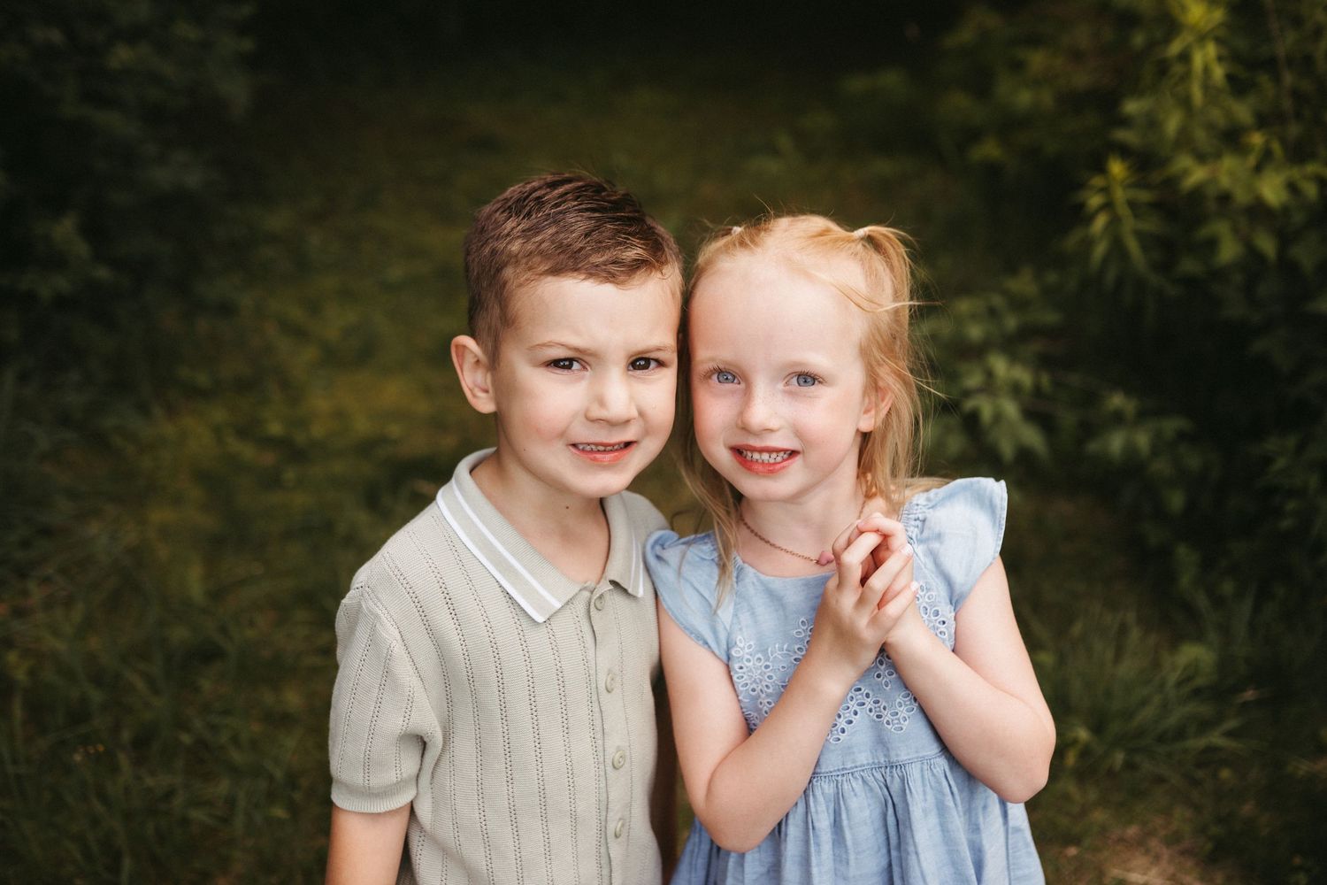 Young children in coordinated outfits sharing sweet moments outdoors.