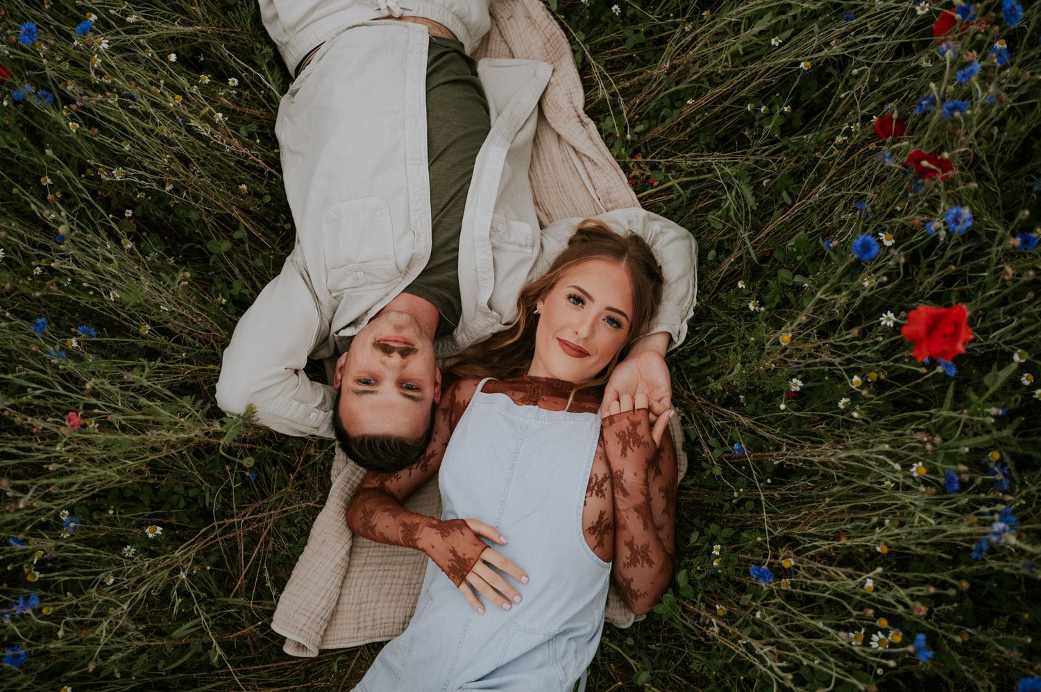 Tender moment shared between couple in flowering meadow with red poppies.