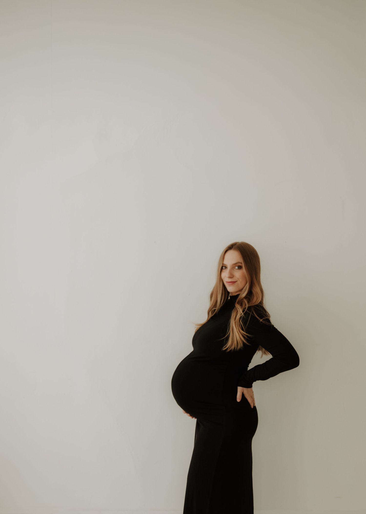Dramatic black and white maternity portraits against a minimalist white background.