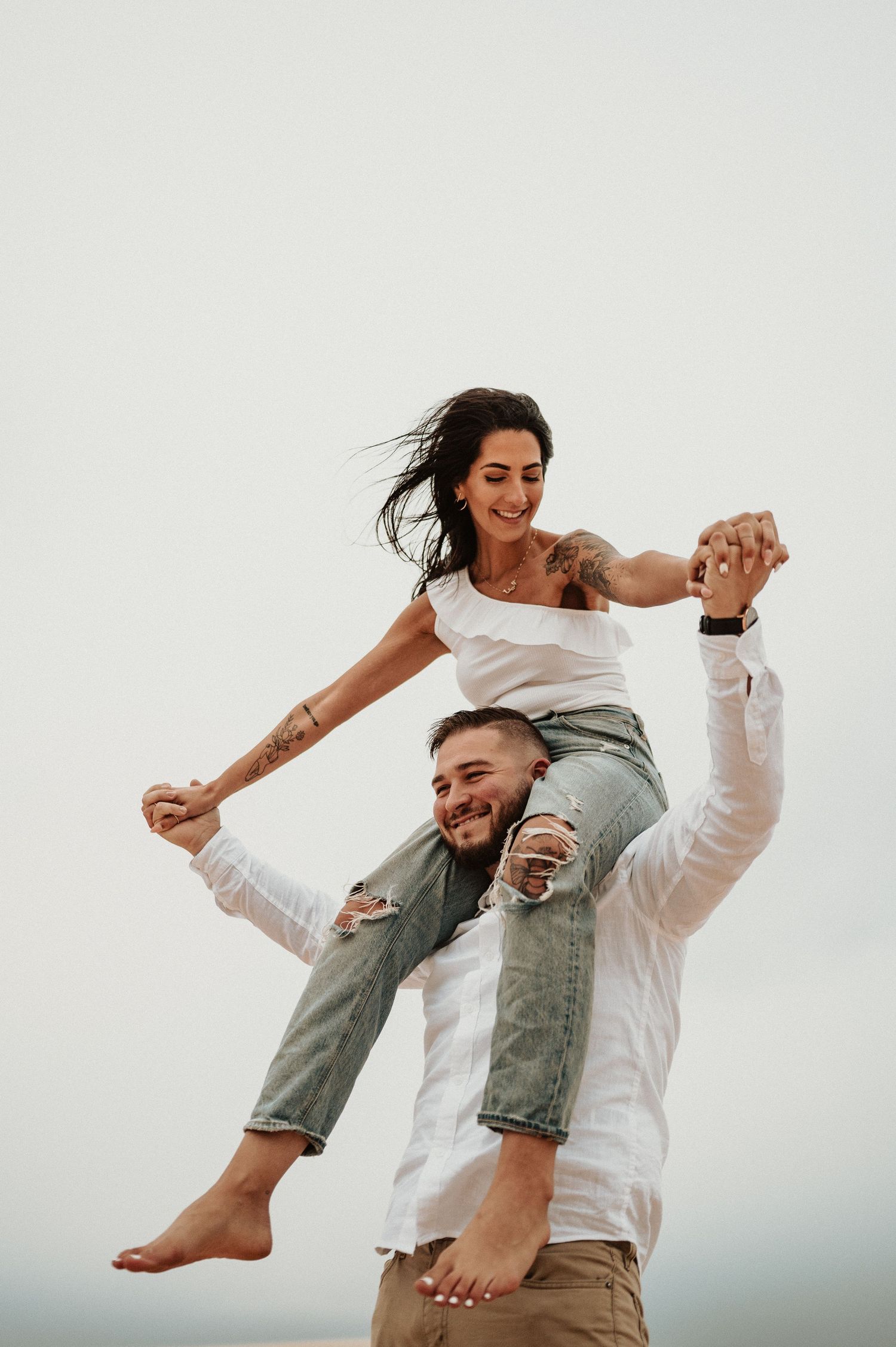 A couple creates a fun shoulder-riding pose during their desert photoshoot.