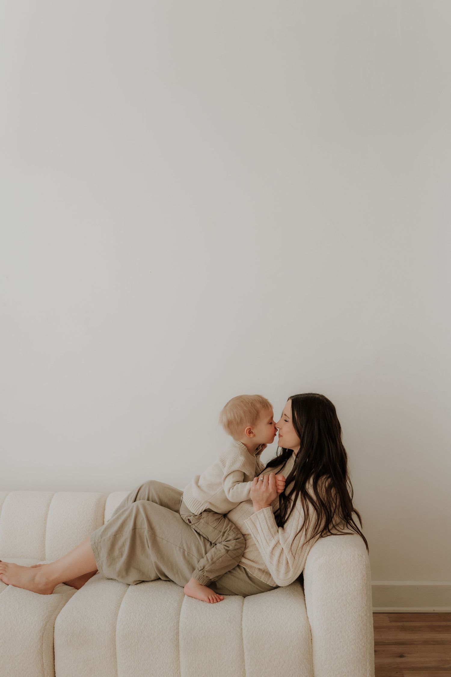 Cozy indoor maternity session on a white couch with soft natural lighting.