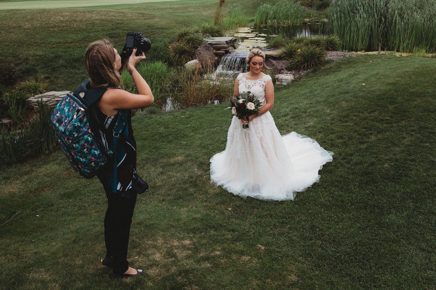 Wedding photographers capturing shots of couple in outdoor garden setting.