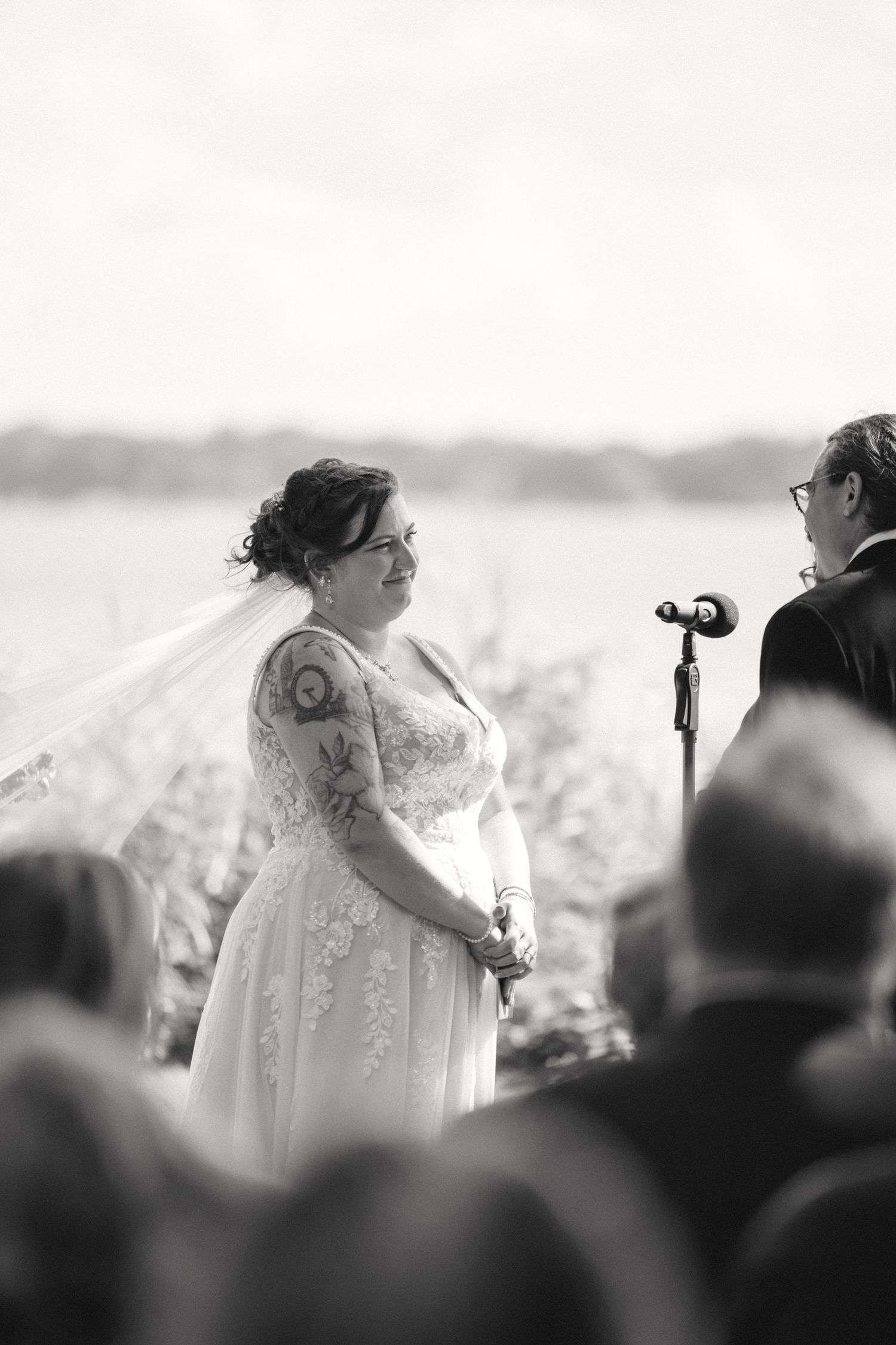 Black and white photo of an outdoor wedding ceremony with guests seated in the foreground.