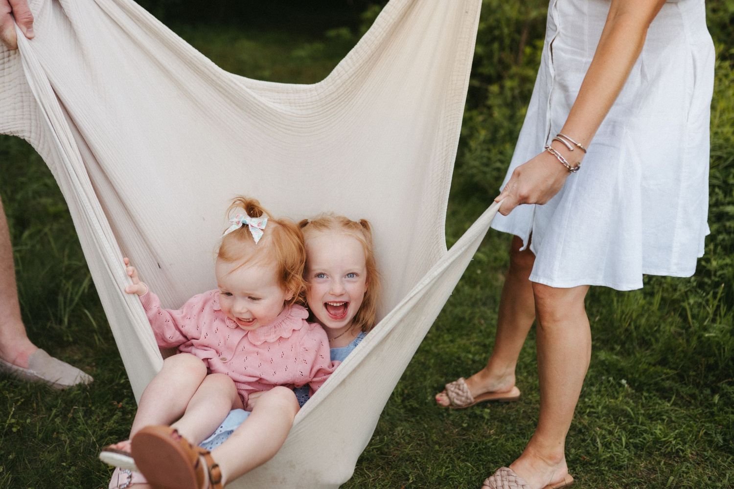 Two young children share joyful moments while relaxing in a white hammock.
