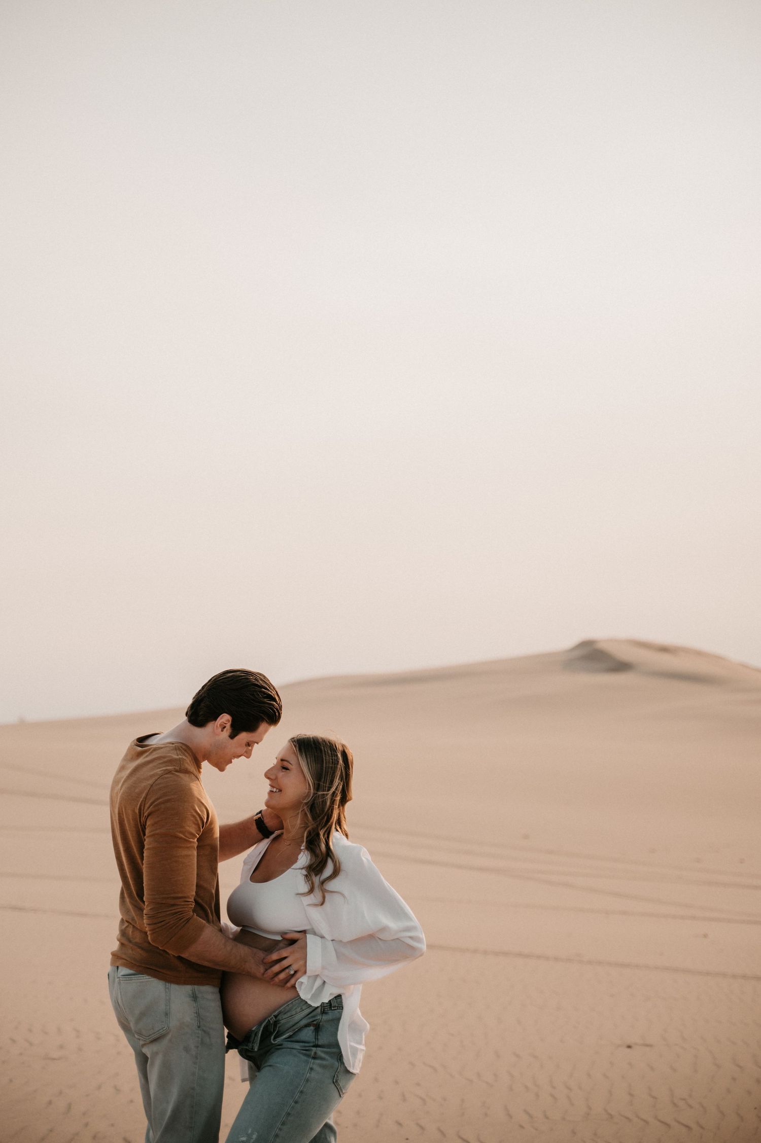 Couple sharing tender moment during desert maternity photography session.