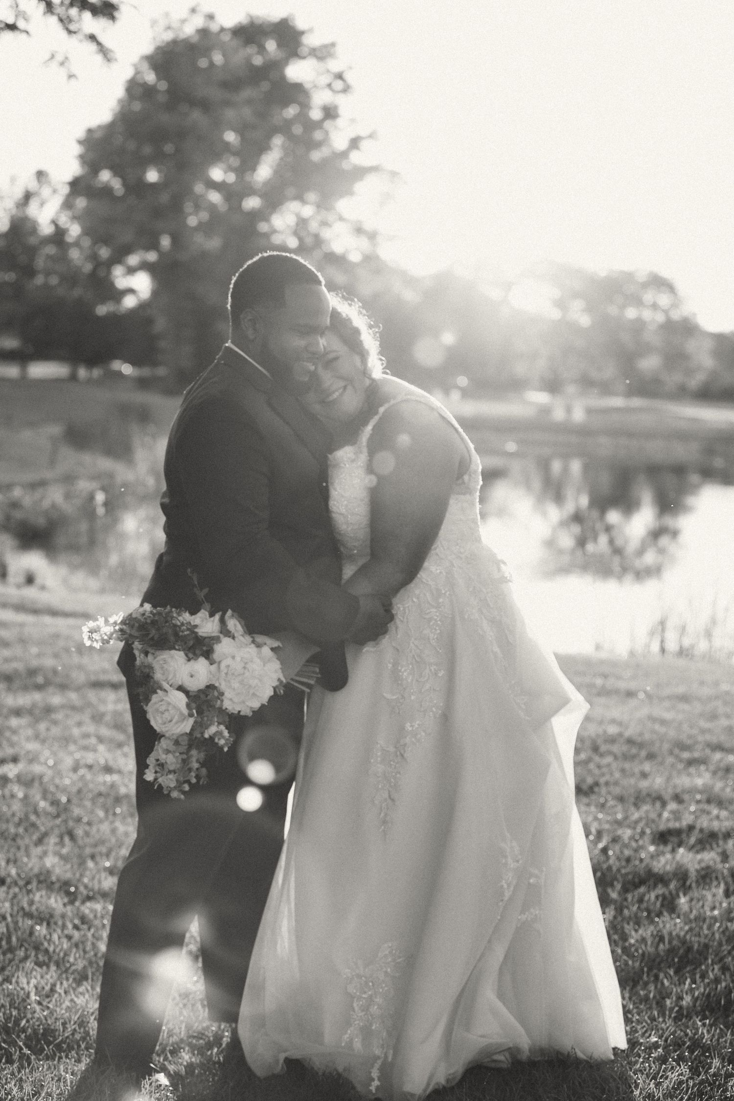 Silhouetted couple embracing by lake during sunset wedding photoshoot.