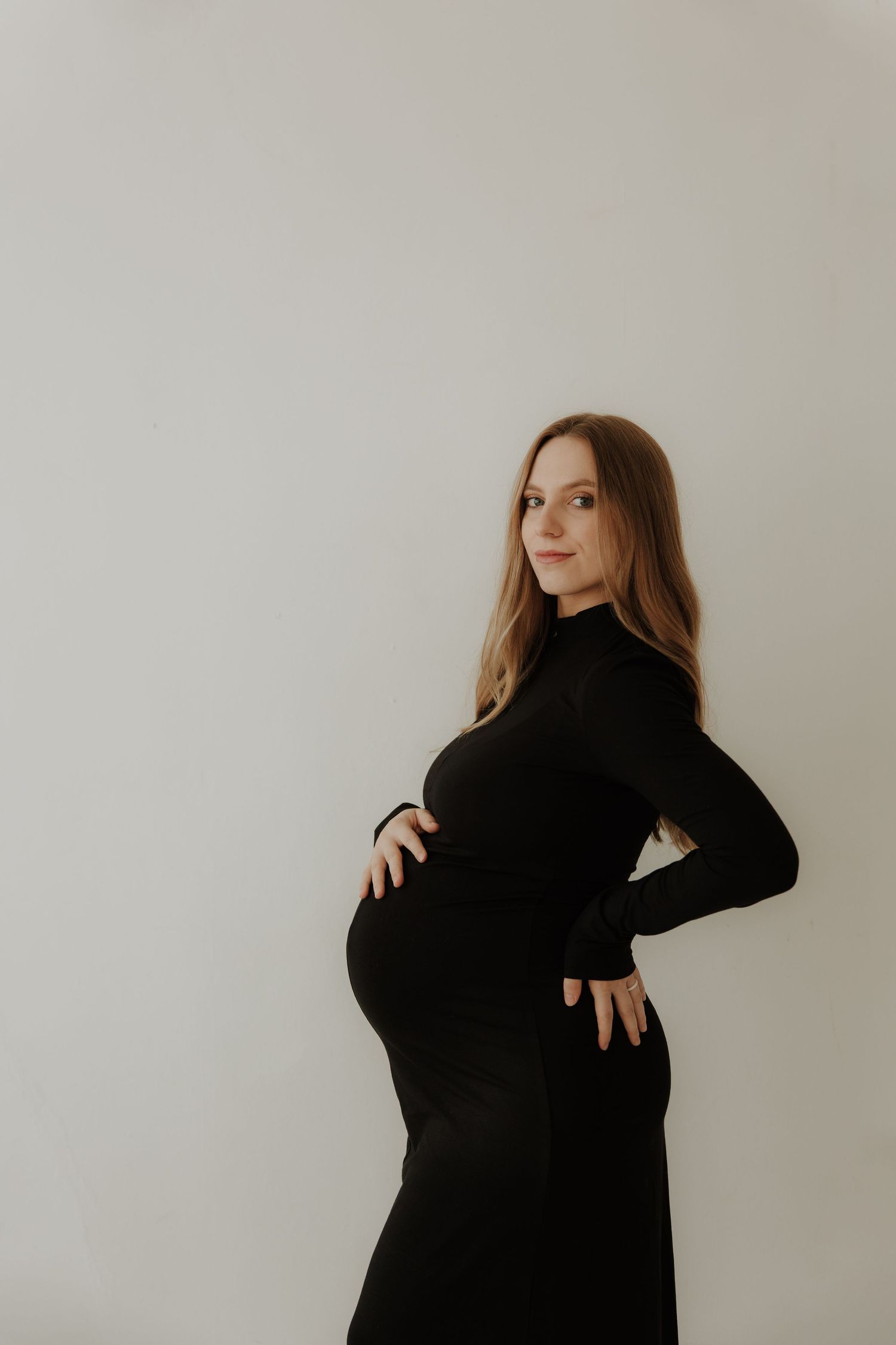 Elegant maternity portraits in black dress showing different poses against neutral backdrop.