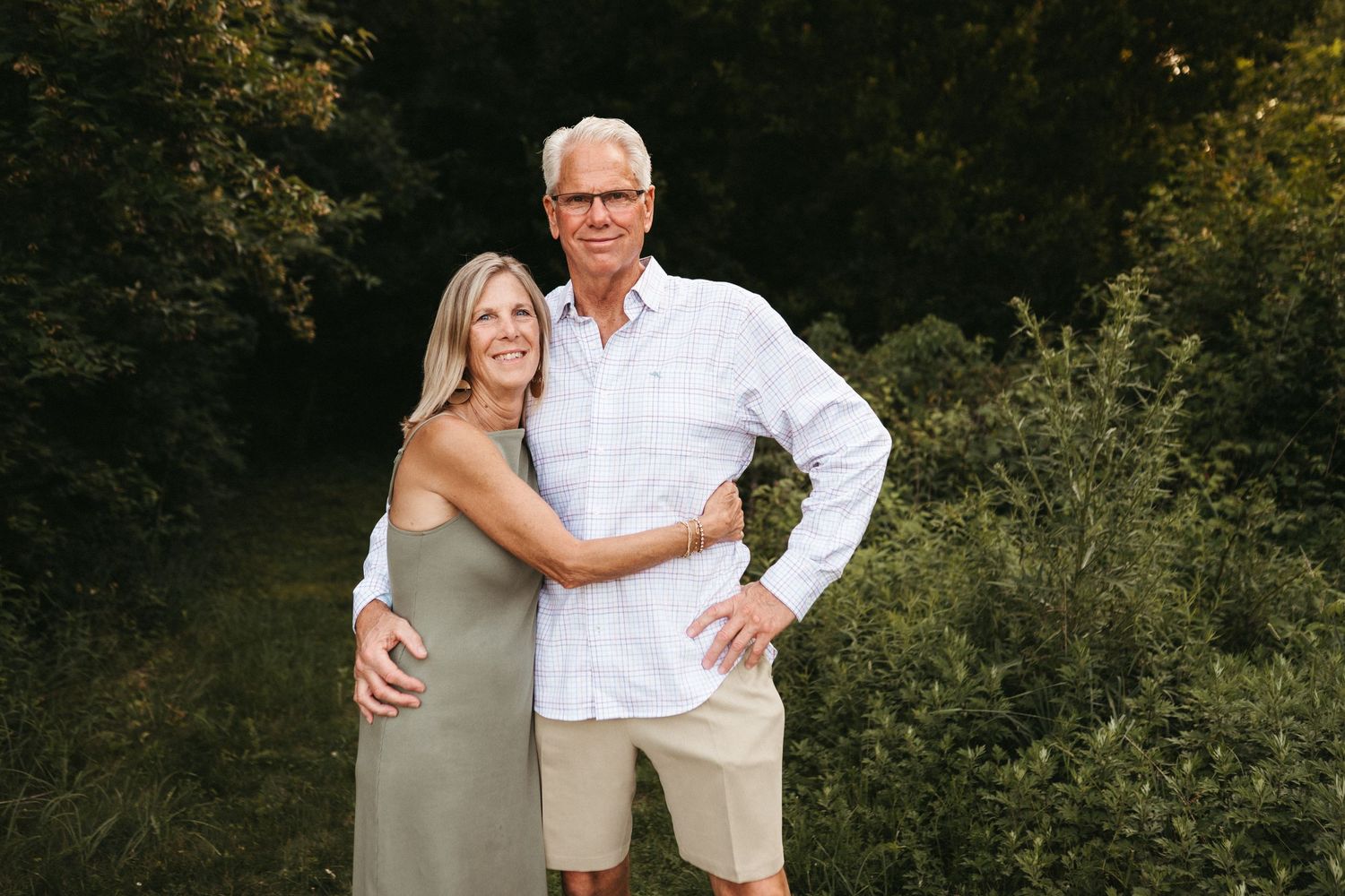 Family members share tender moments together during sunset photoshoot in wooded area.