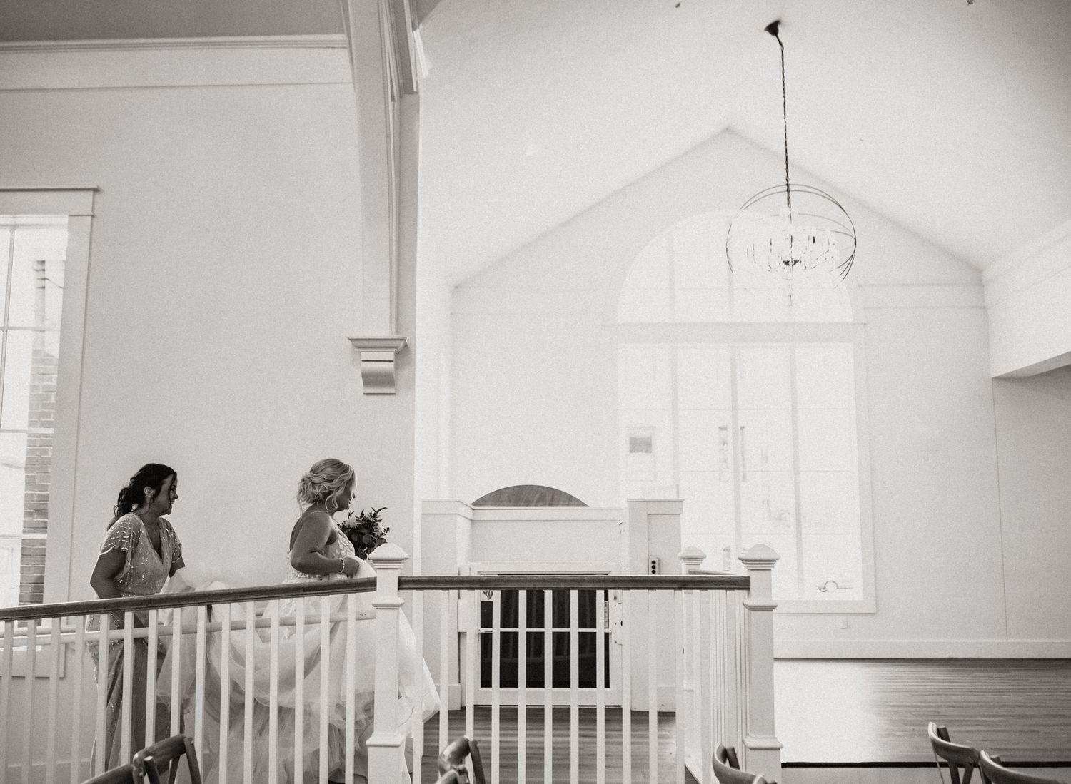 Two people standing at a white balcony railing inside a bright church interior.