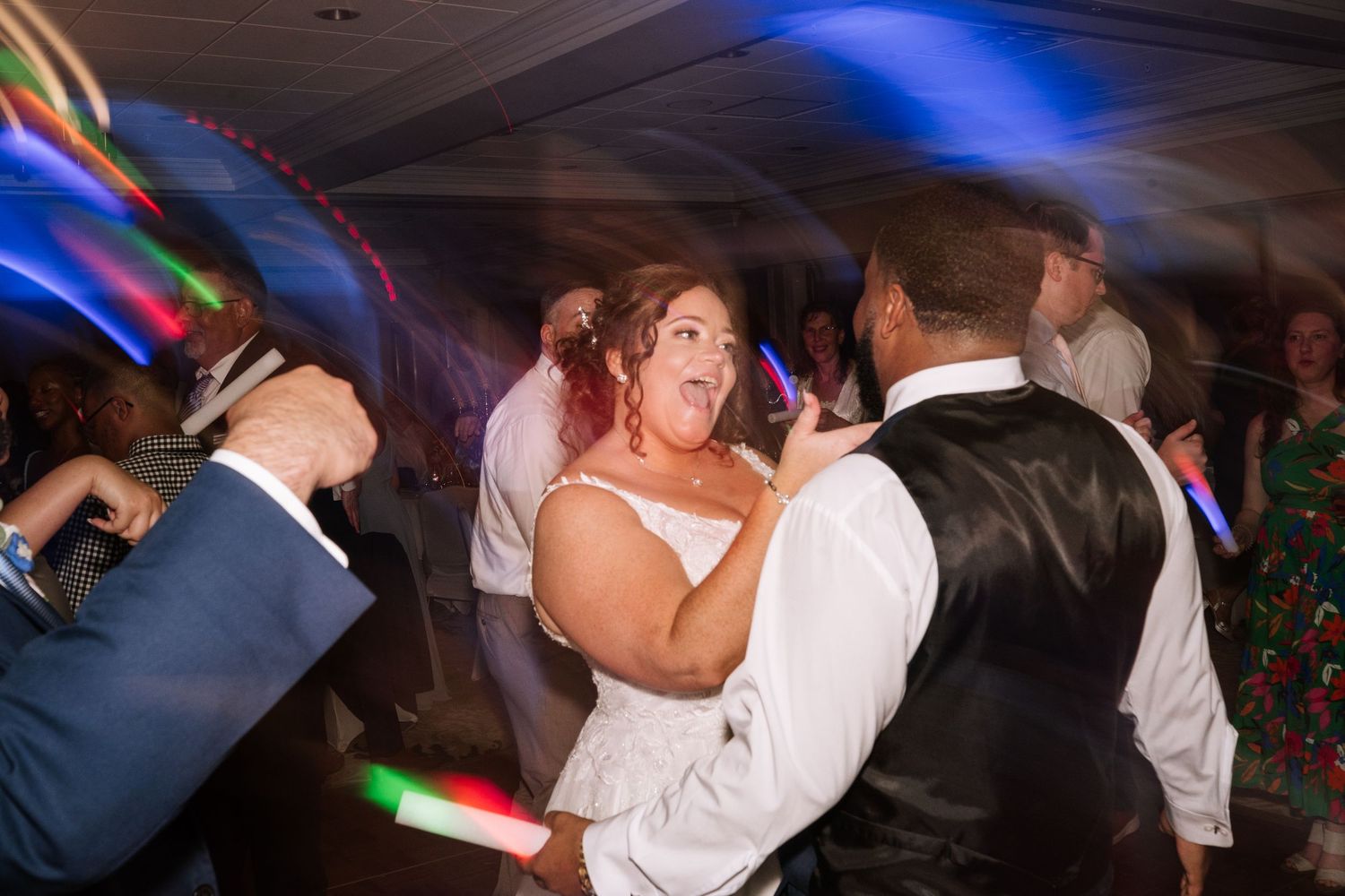 Wedding reception dance floor with colorful lighting and dancing guests.