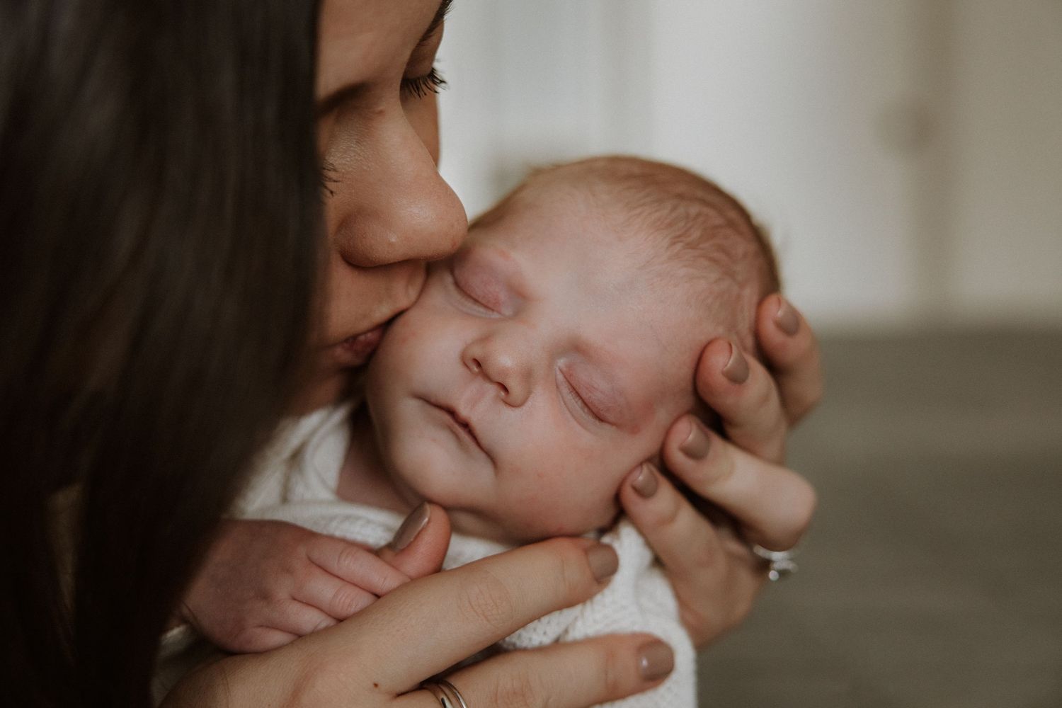 Close-up shots showing gentle moments with a sleeping newborn baby in soft lighting.