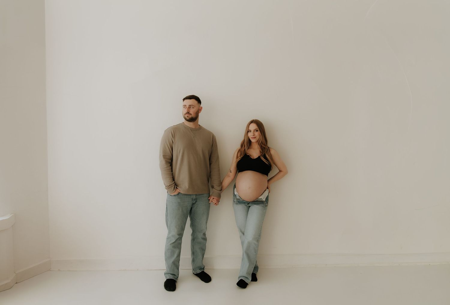 A series of artistic photographs showing people posing against a white wall in casual clothing.