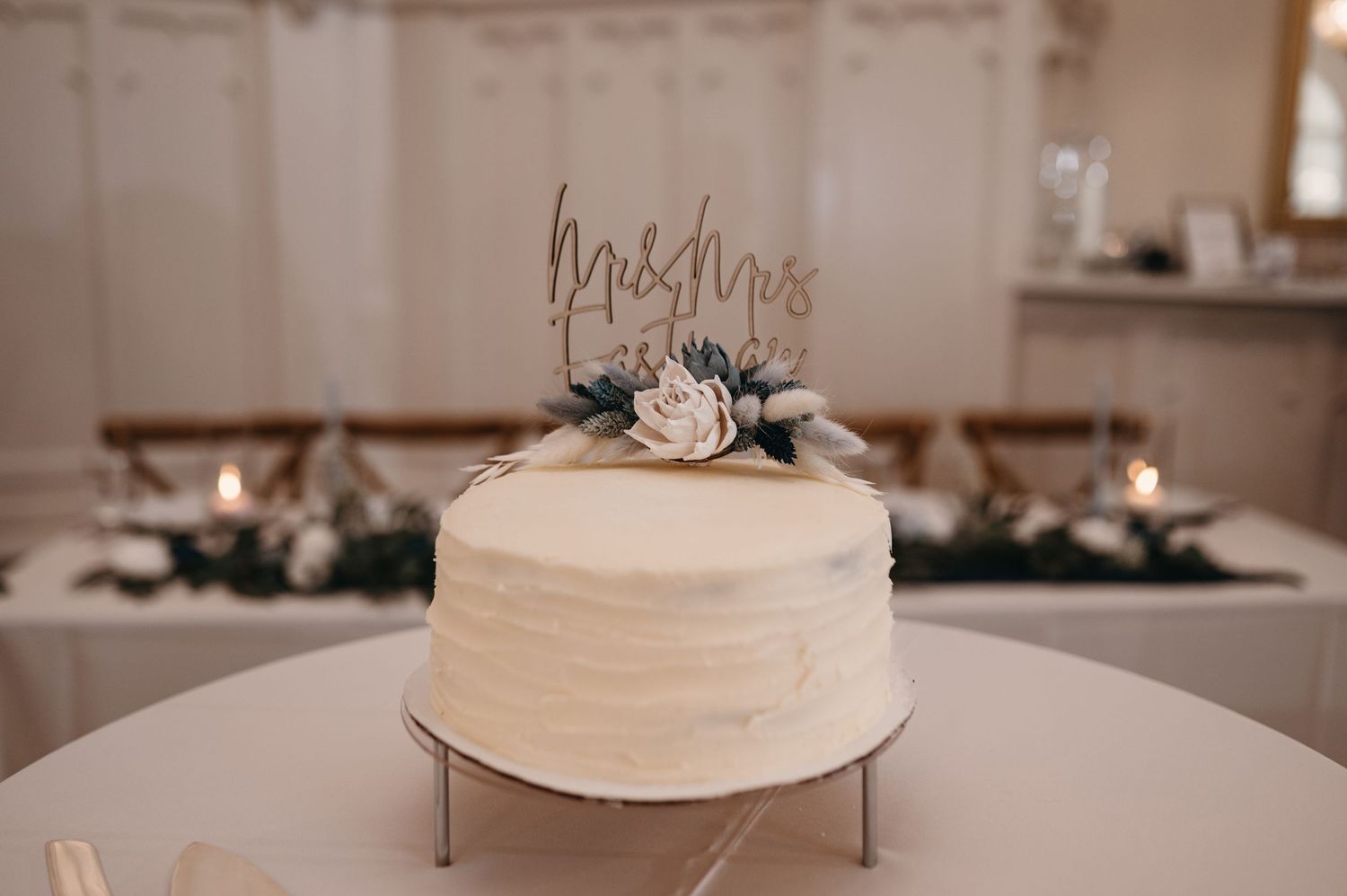 Simple white wedding cake decorated with fresh flowers and a delicate topper.
