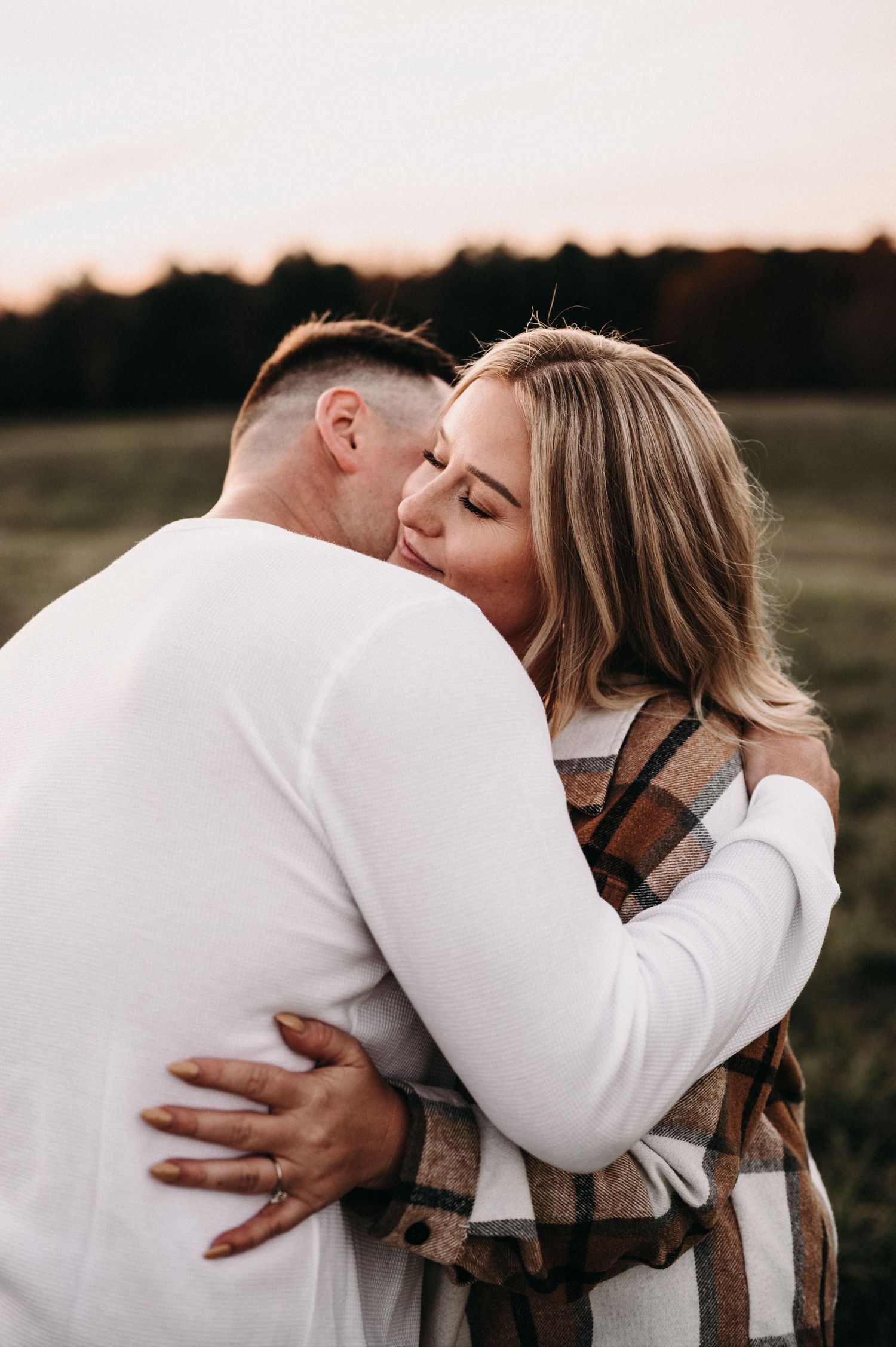 Tender moment between couple hugging in outdoor autumn setting.