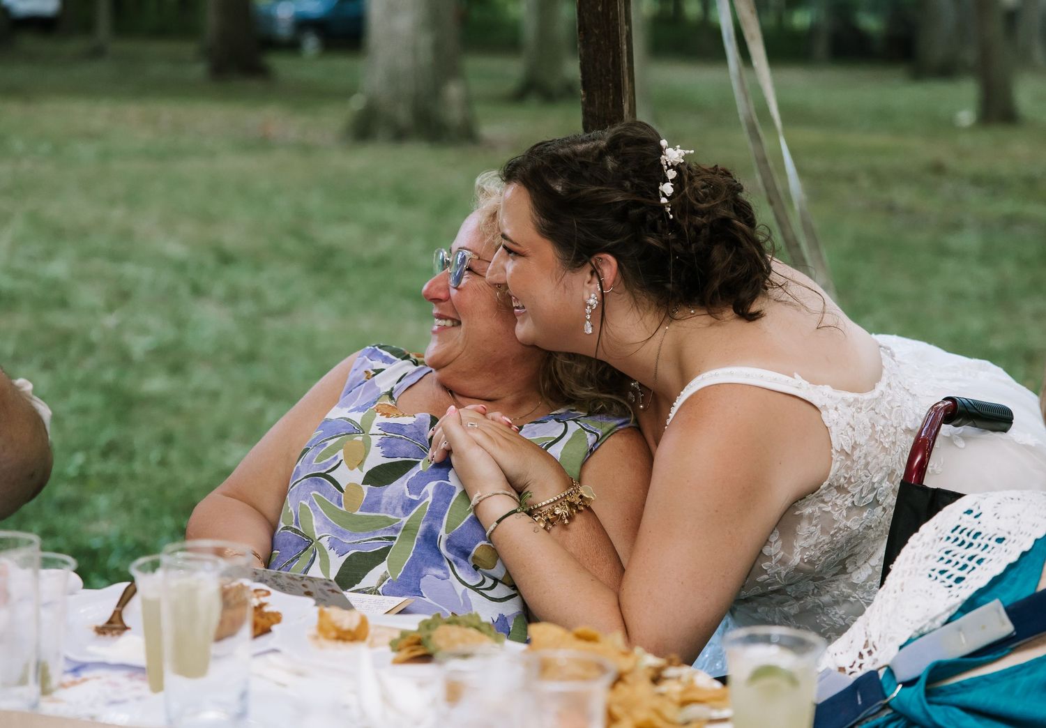Wedding reception guests laughing and enjoying a meal at outdoor tables.