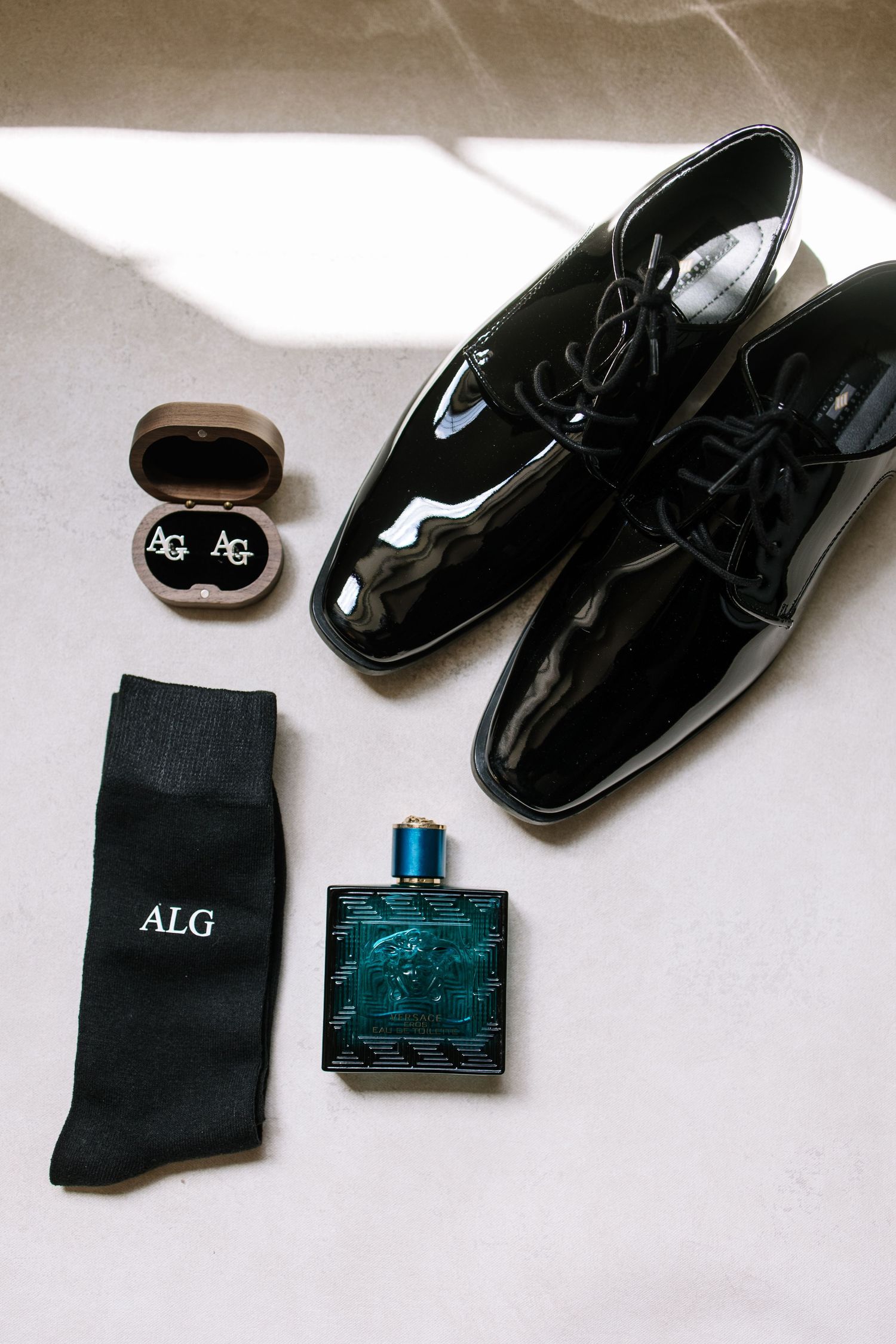 Black dress socks and patent leather formal shoes laid out with monogrammed accessories.
