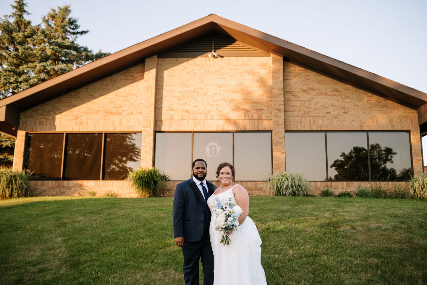 Wedding couple posing in front of modern church building during golden hour.