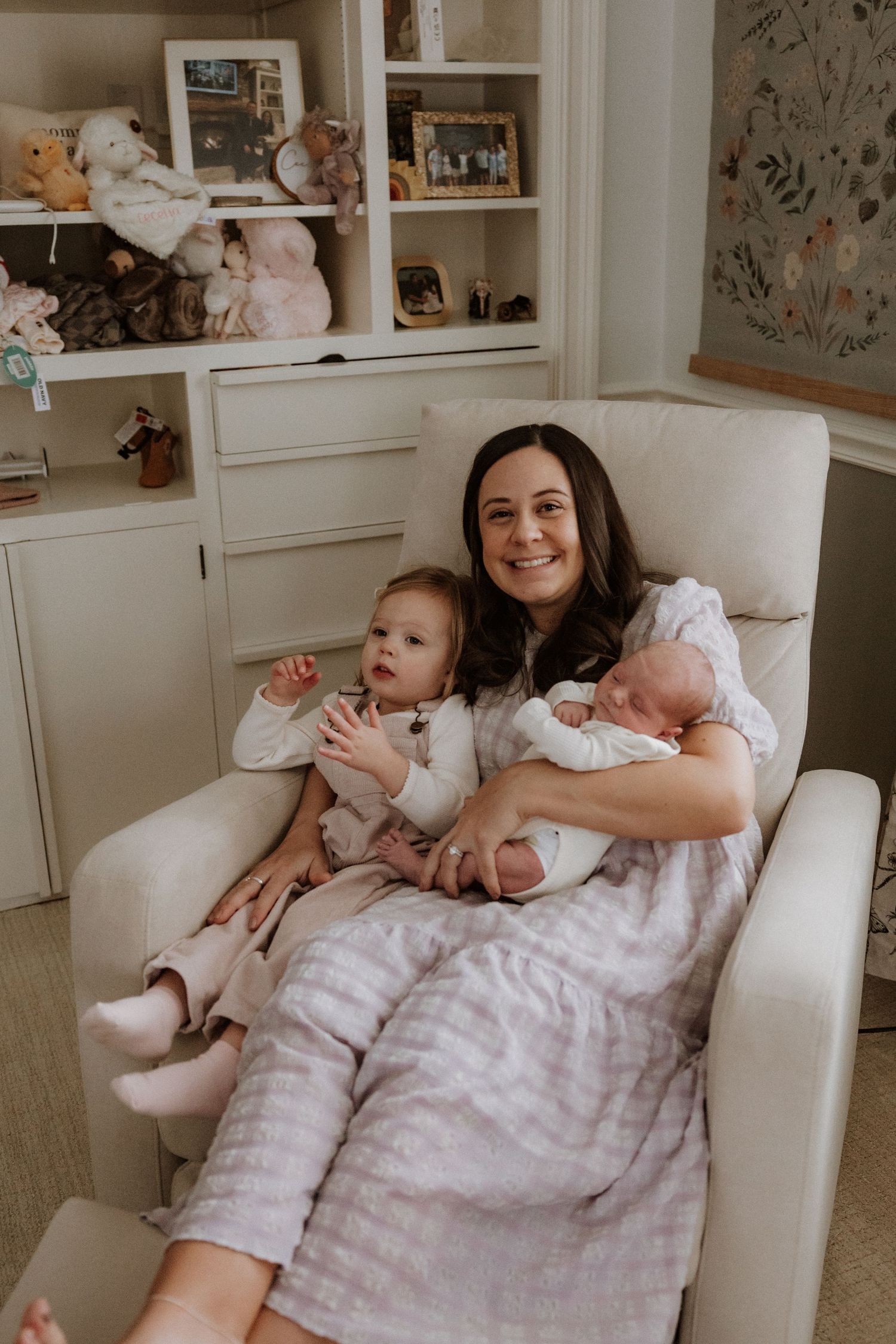 Family lounging together on a white couch in a cozy living room with floral wallpaper.