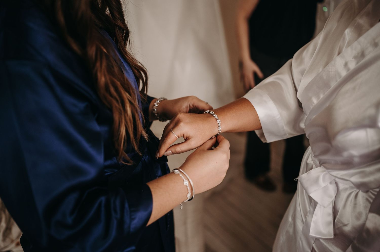 Close-up of hands fastening a bracelet during wedding preparations.