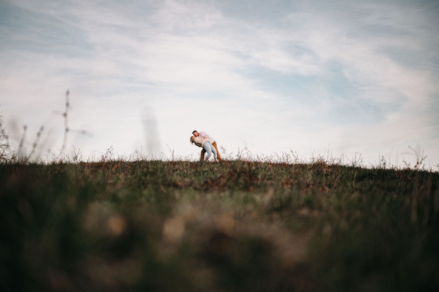 Artistic landscape photo of two figures embracing on a distant hilltop.